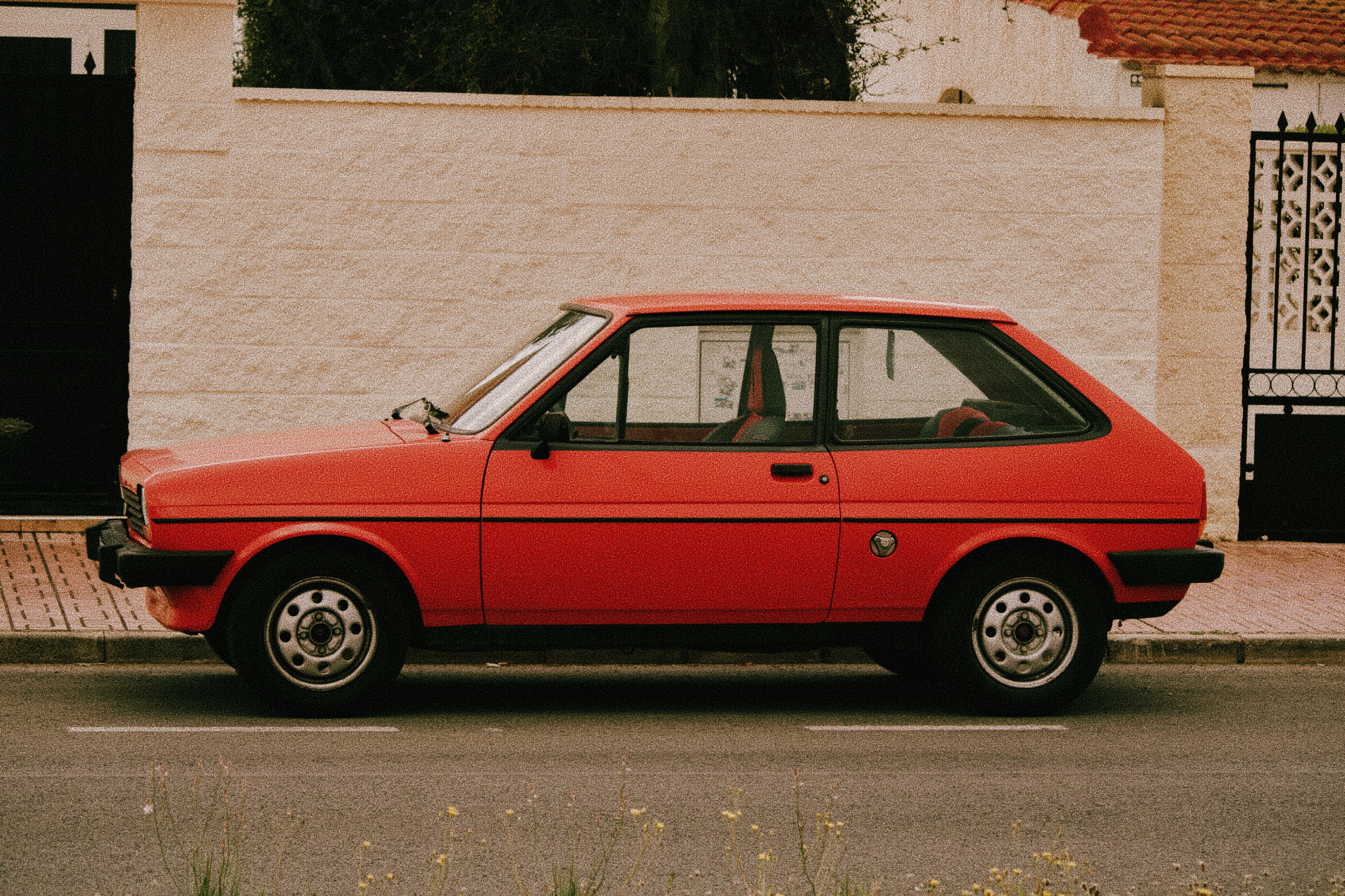 Gratuit Une voiture classique rouge à hayon garée à côté d'un mur de pierre blanche à Torrevieja, en Espagne. Photos