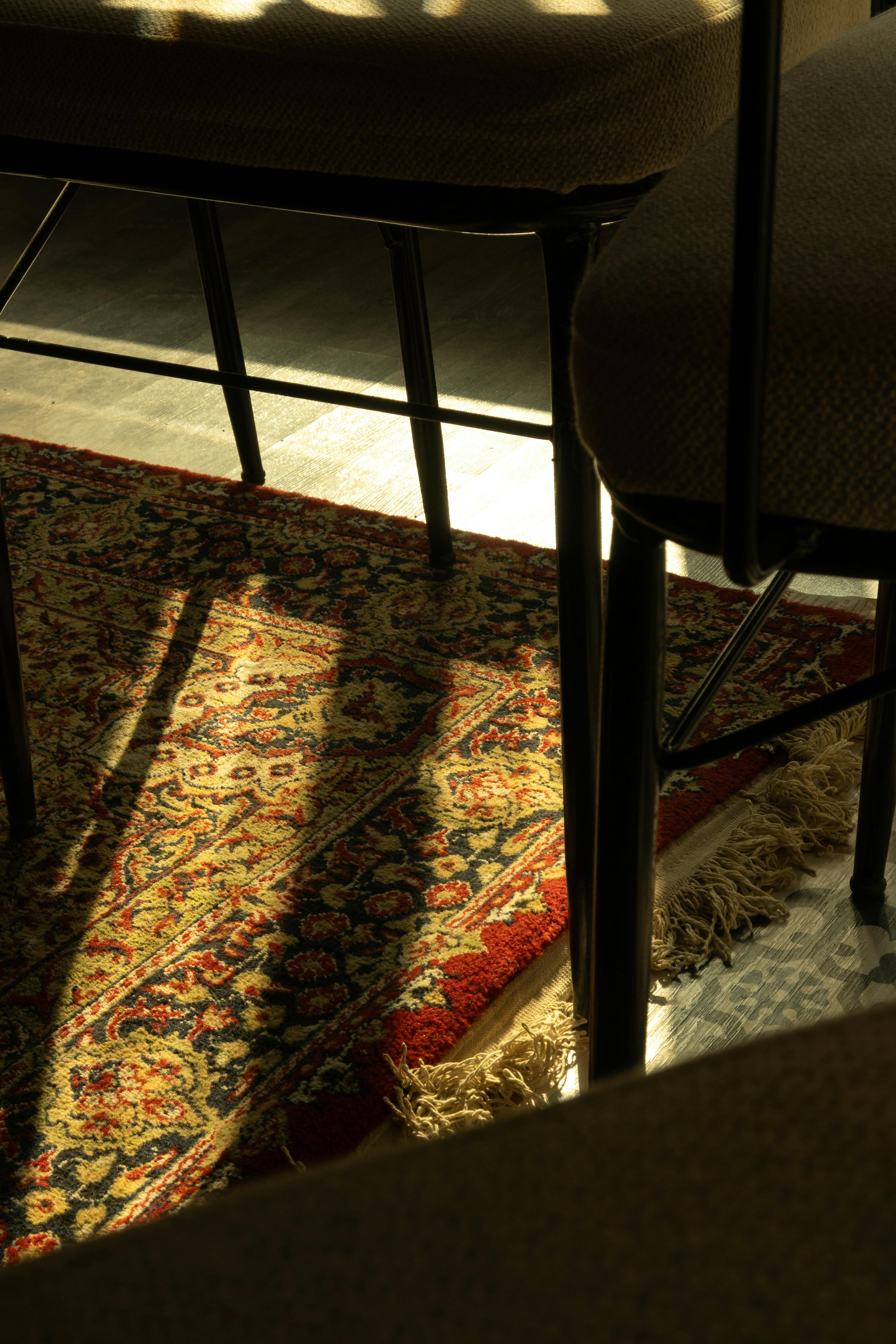 grátis A luz do sol que filtra pelas cadeiras ilumina um tapete oriental com padrões ricos. Foto profissional