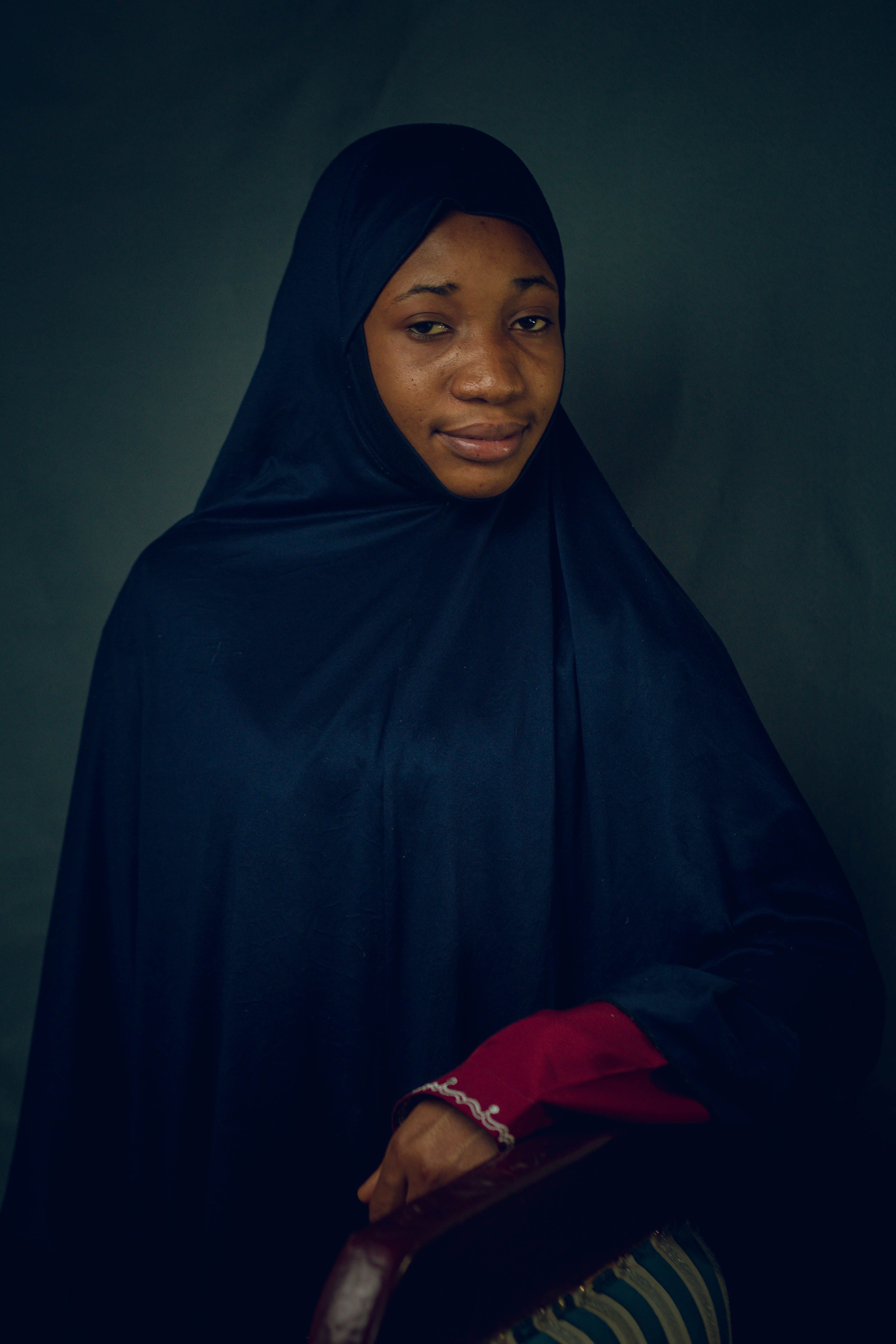 A serene portrait of an adult woman wearing a traditional hijab against a neutral background.