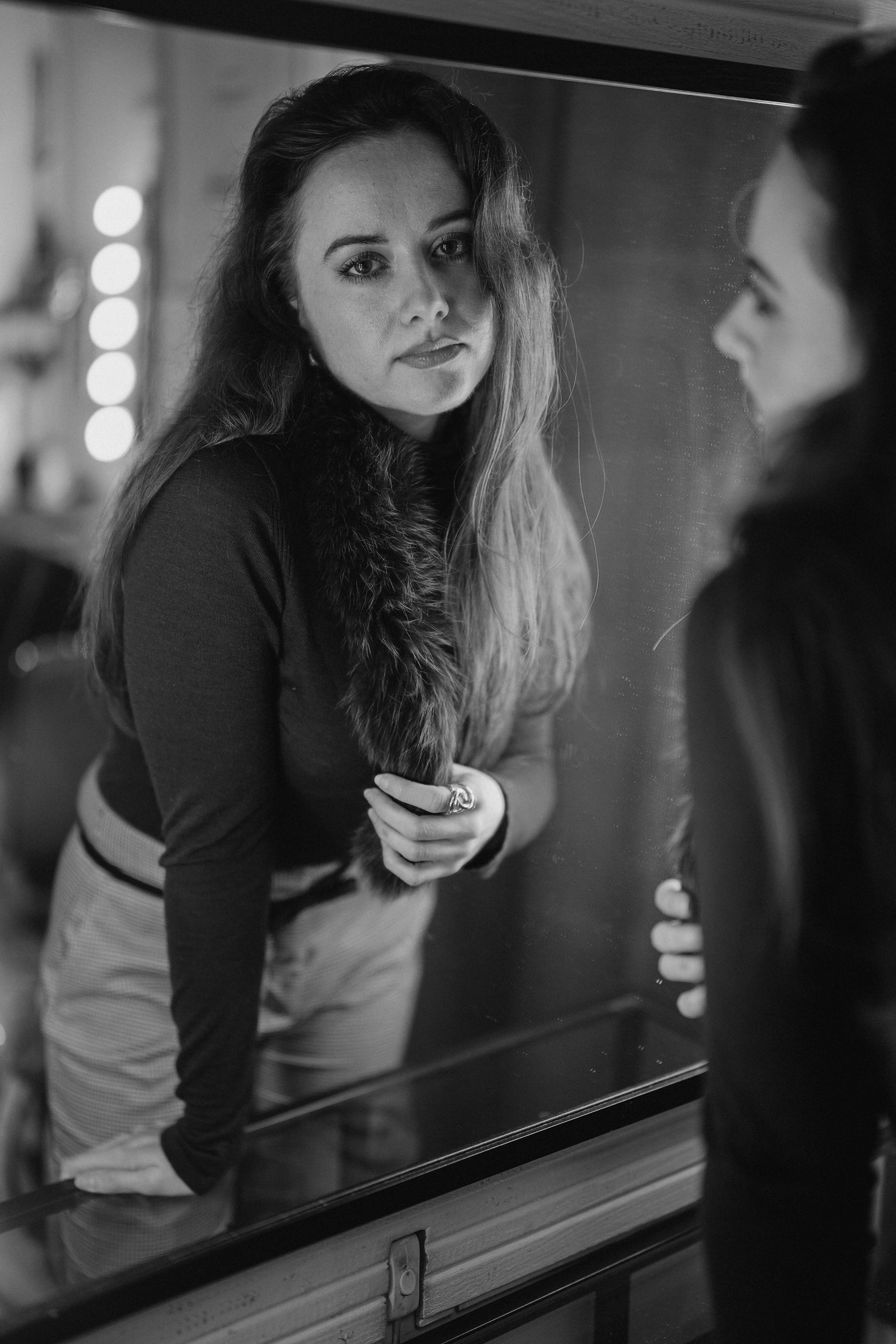 Безкоштовне Чорно-білий портрет жінки, яка дивиться в дзеркало, створюючи рефлексивний настрій. стокове фото