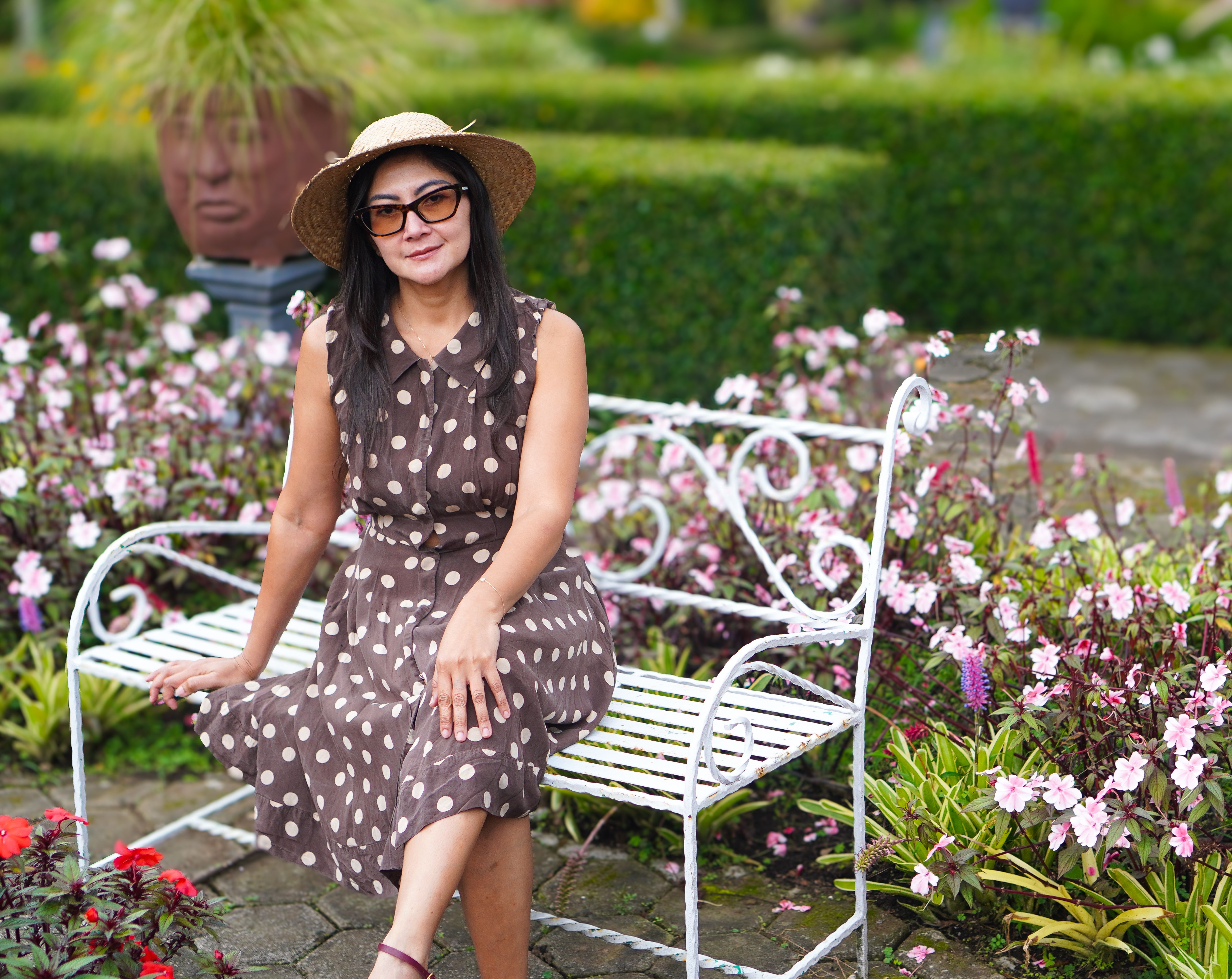 Woman in Polka Dot Dress Sitting on Garden Bench · Free Stock Photo