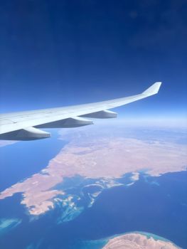 A stunning aerial shot of a coastline from an airplane, showcasing clear skies and blue waters.