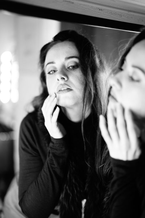 Free Black and white portrait of a woman looking into a mirror, reflecting on self. Stock Photo