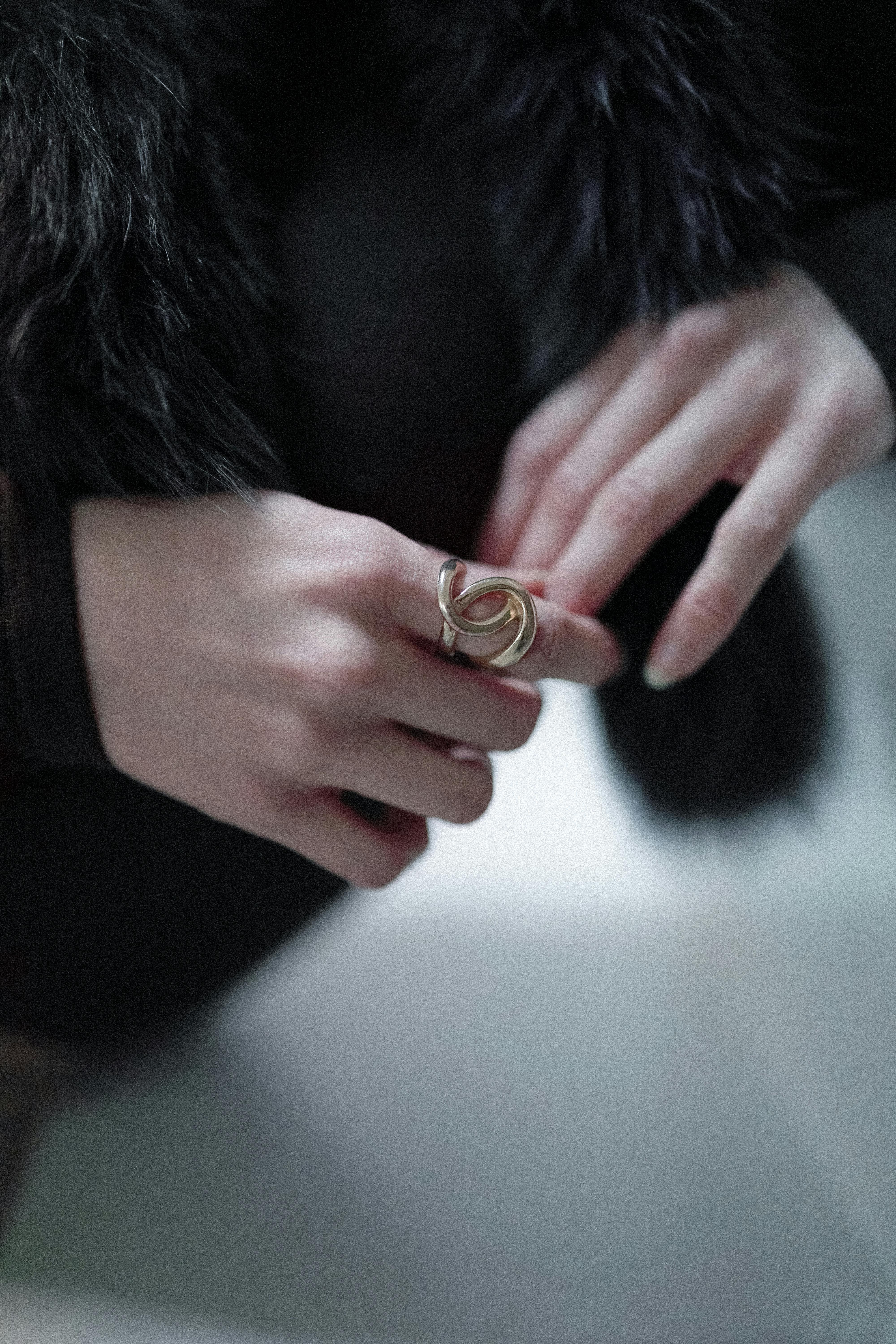 무료 금반지와 우아한 모피 코트로 장식된 여성의 손을 클로즈업하여 패션 액세서리를 돋보이게 했다. 스톡 사진