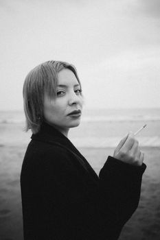 Captivating monochrome portrait of a woman standing on a beach, exuding mood and introspection.