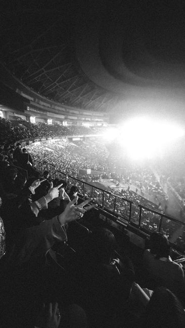 Vast audience at a live concert in an indoor arena, lit by d