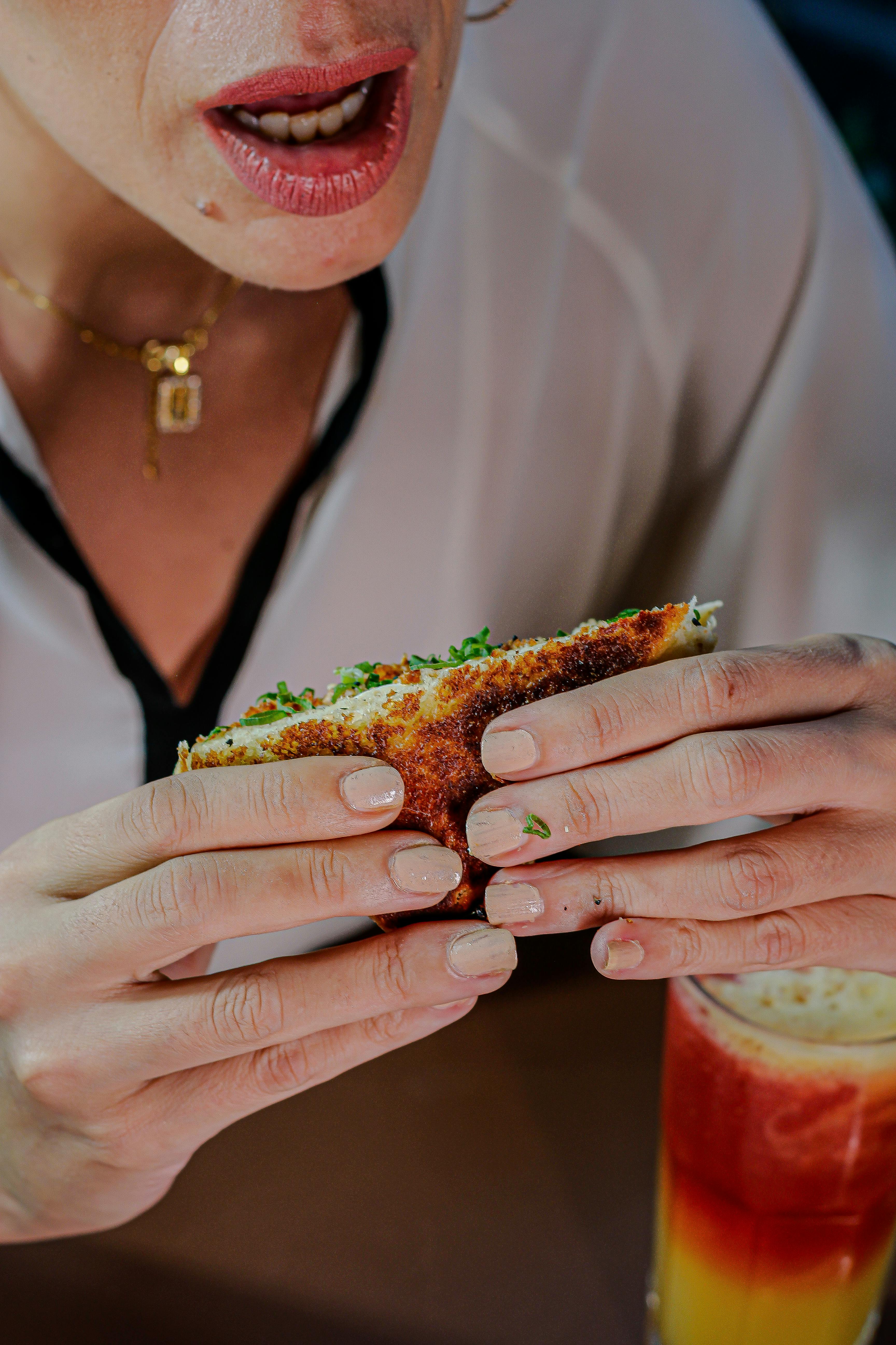 免費 一位女士一邊吃三明治，一邊喝著飲料，展現了輕鬆休閒的用餐氛圍。 圖庫相片