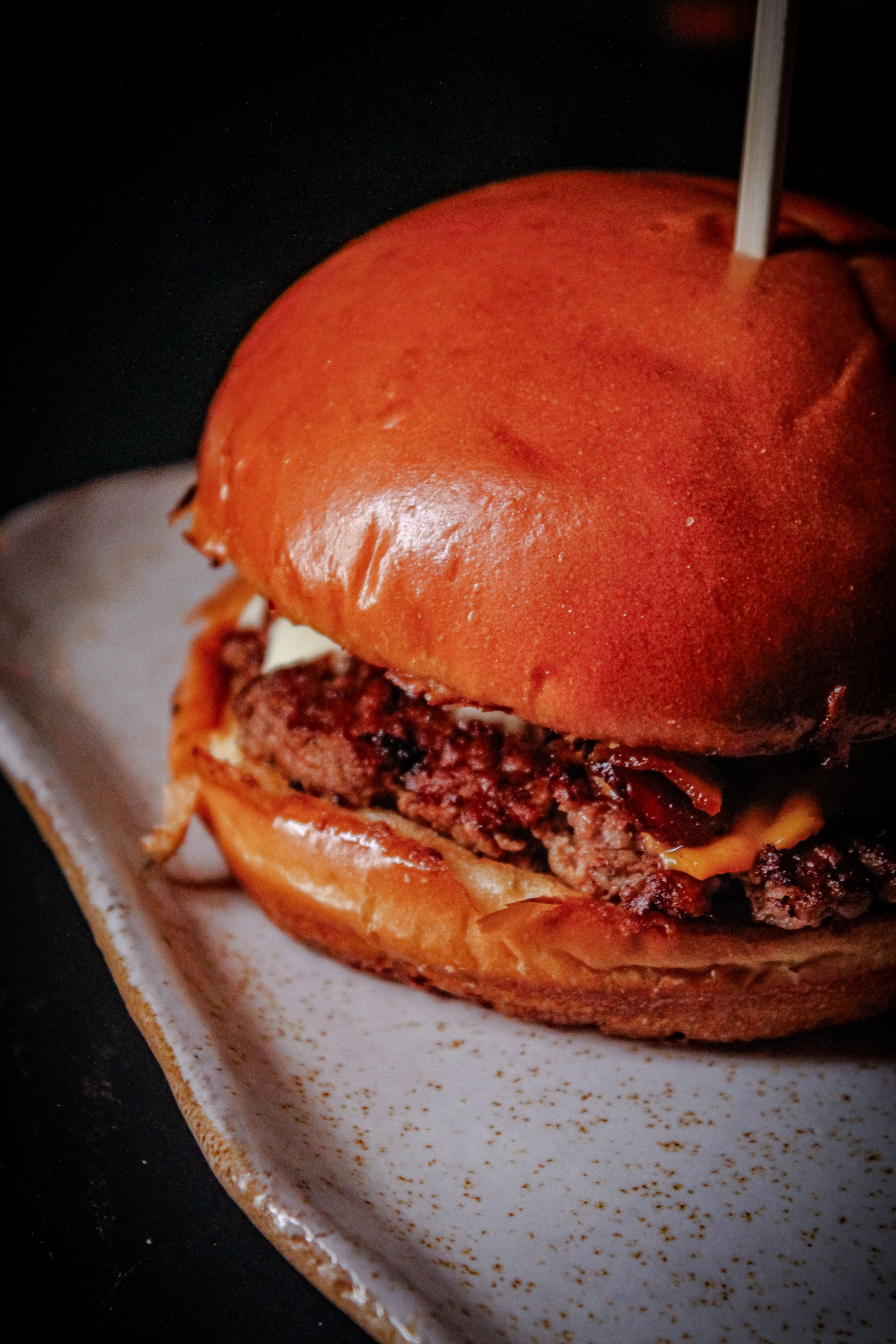Close-up of a juicy cheeseburger with fresh ingredients on a ceramic plate, perfect for food lovers.
