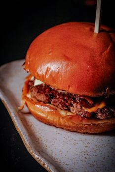 Close-up of a juicy cheeseburger with fresh ingredients on a ceramic plate, perfect for food lovers.