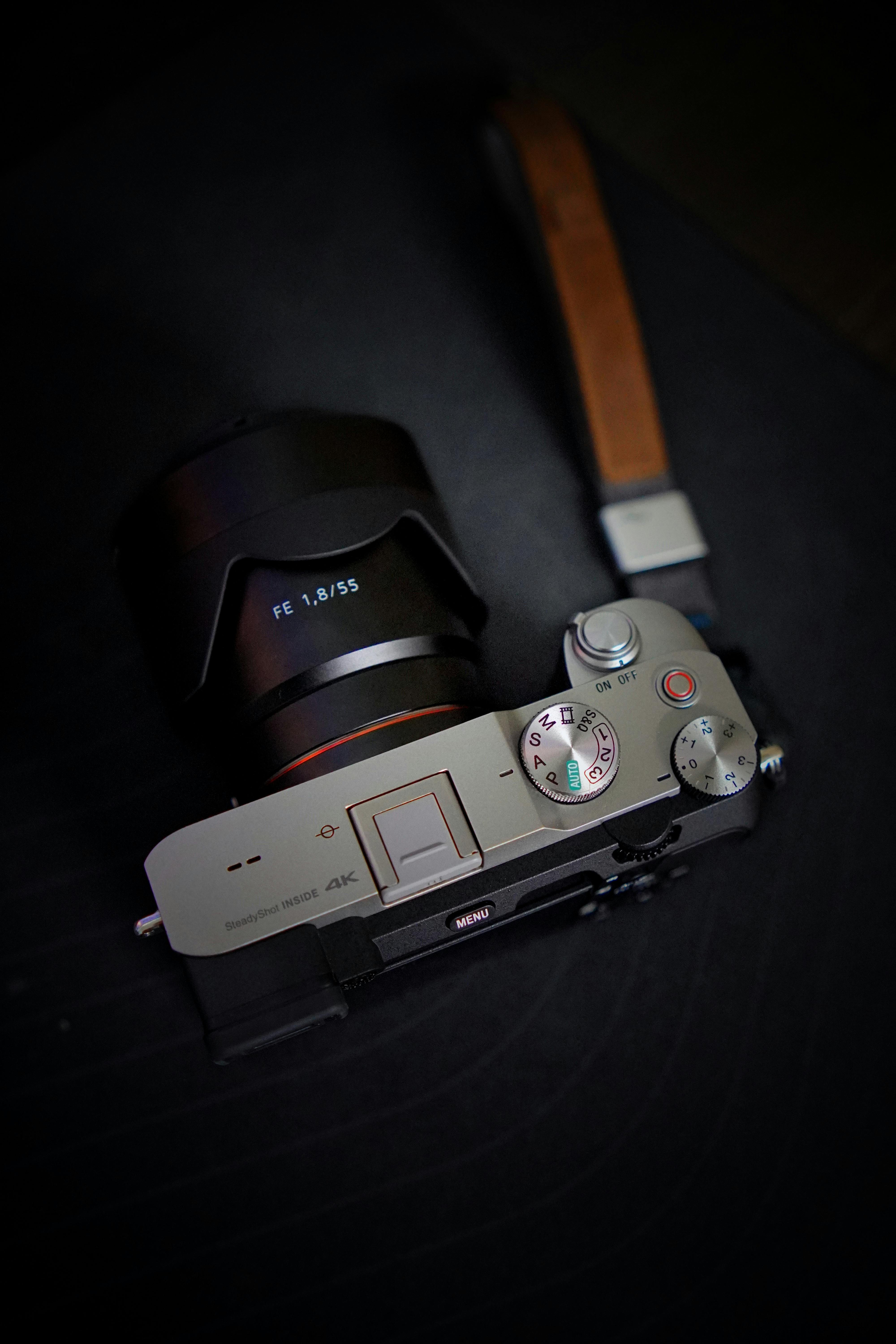 Zadarmo Moderný fotoaparát s objektívom na tmavom pozadí, ktorý predstavuje elegantný dizajn a detaily pre nadšencov fotografie. Fotka z fotobanky