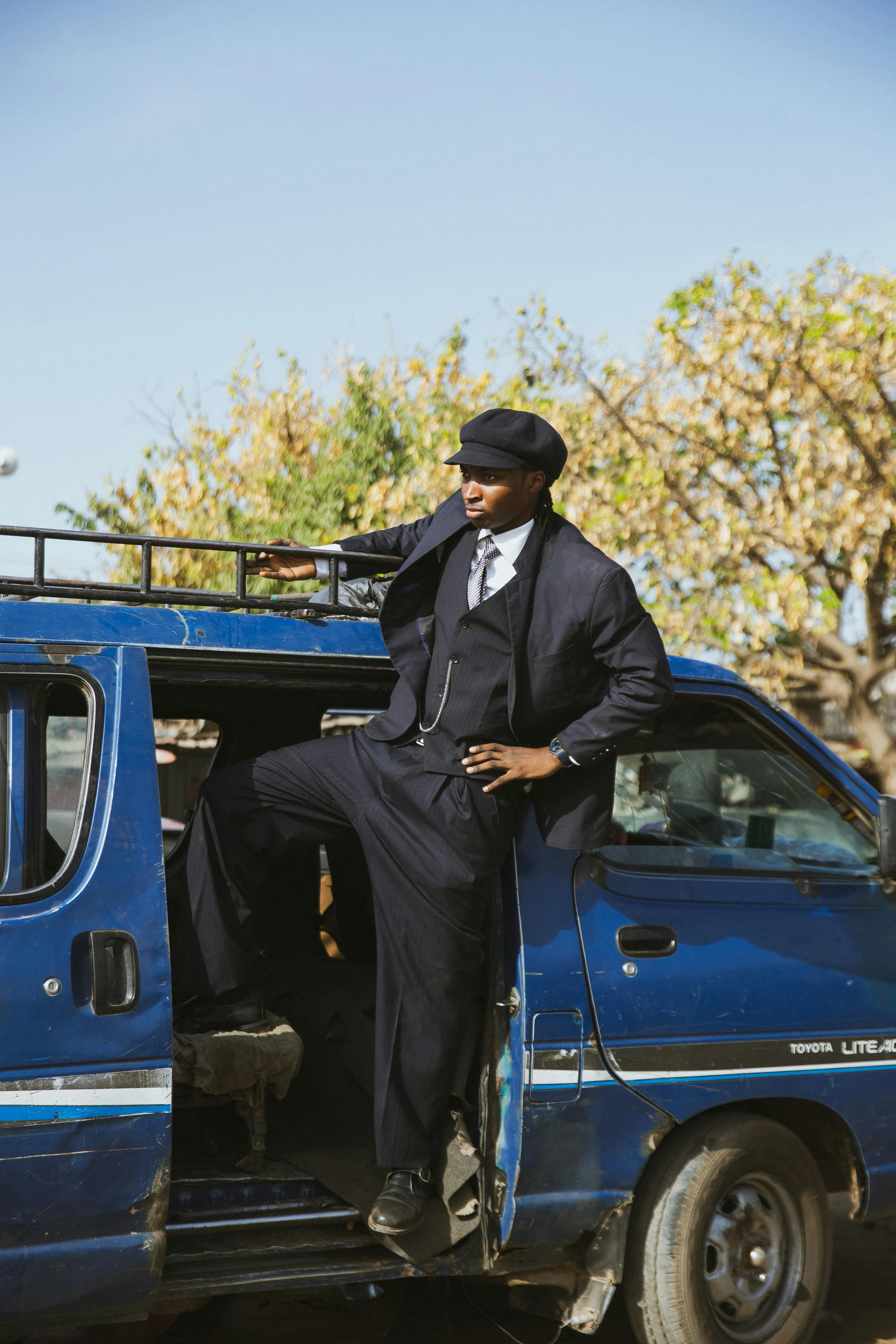 免费 身着复古服装的男子从一辆蓝色面包车中走出来，展现出都市街头风格。 素材图片