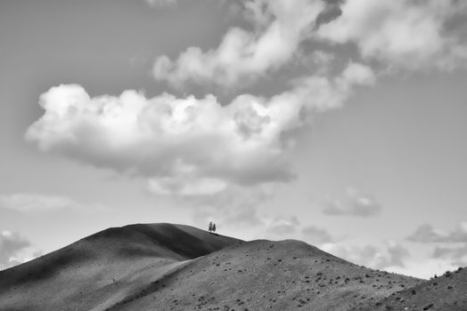A serene black and white landscape of hills under a cloud-filled sky, offering solitude and beauty.