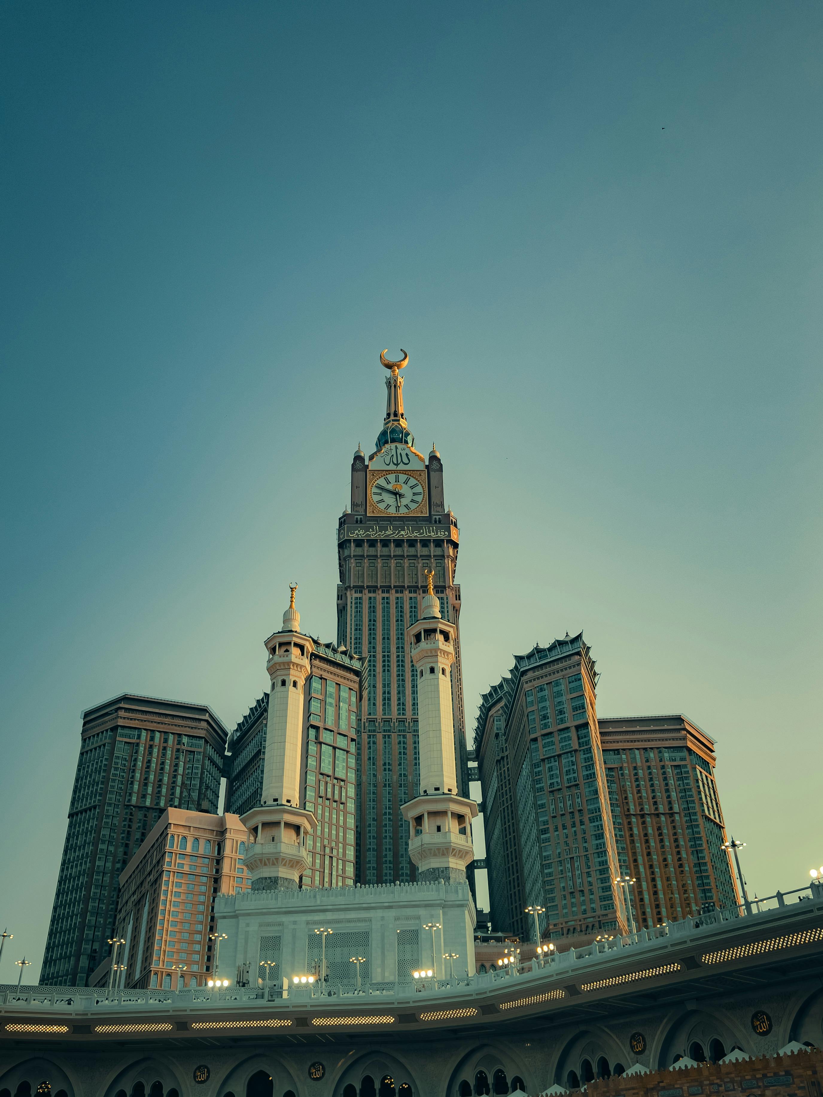 grátis Uma vista deslumbrante das Torres Abraj Al Bait em Meca contra um céu limpo, capturando sua icônica torre do relógio. Foto profissional