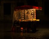 A market vendor sleeping at a street food stall under warm lights at night.