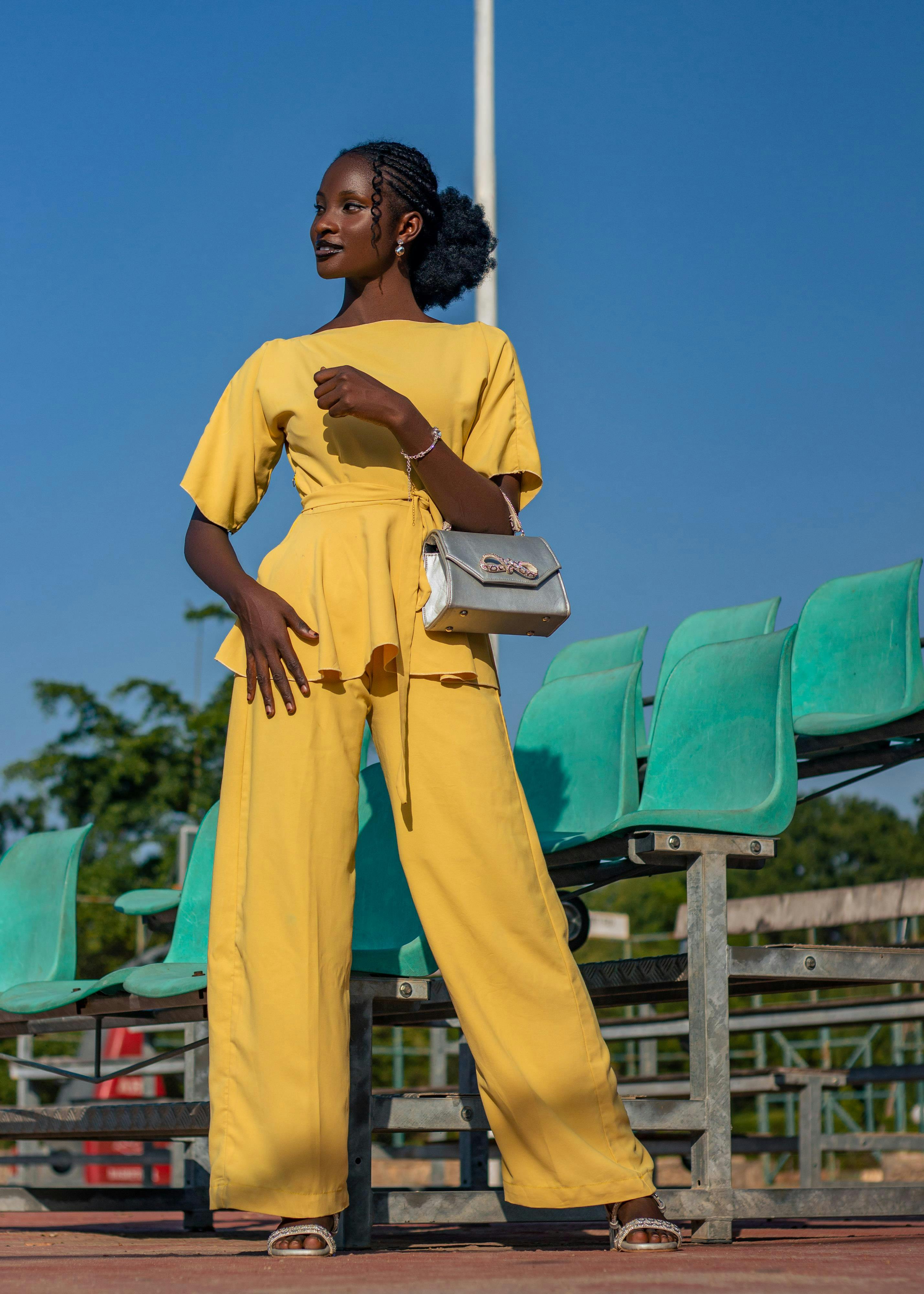 免费 一位自信的女士身穿时尚的黄色连体裤在户外摆姿势，散发出现代时尚气息。 素材图片