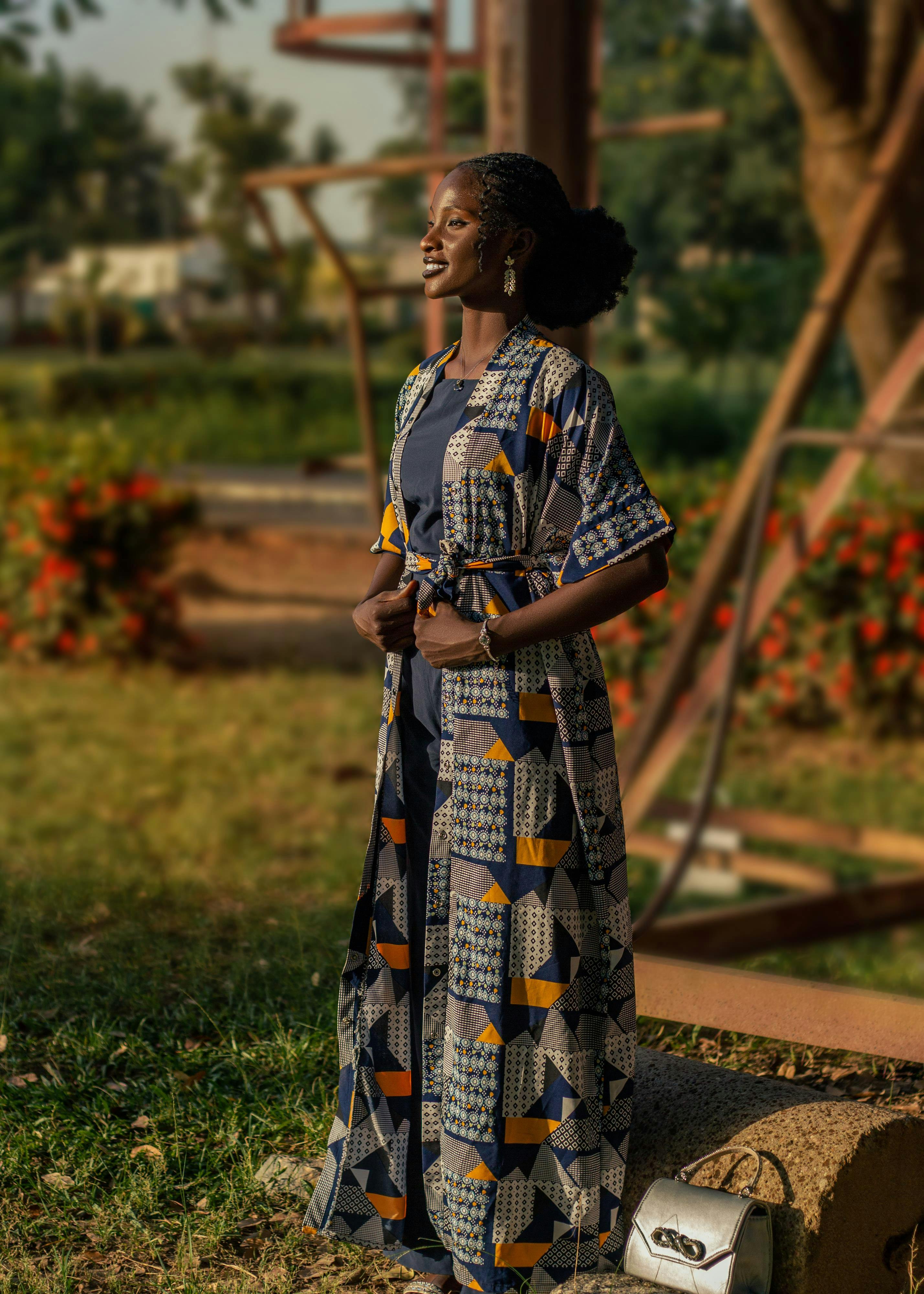 免费 一位身着色彩艳丽的非洲传统服饰的女子在公园里享受着阳光明媚的户外时光。 素材图片