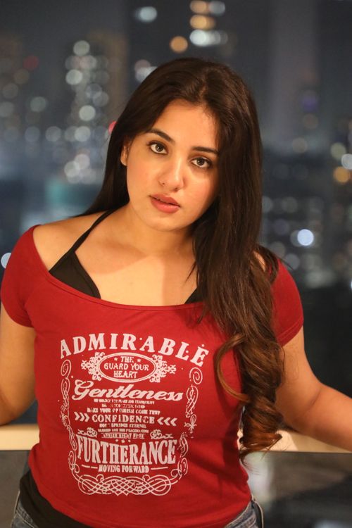 Free Portrait of a young woman wearing red against a city night backdrop. Stock Photo