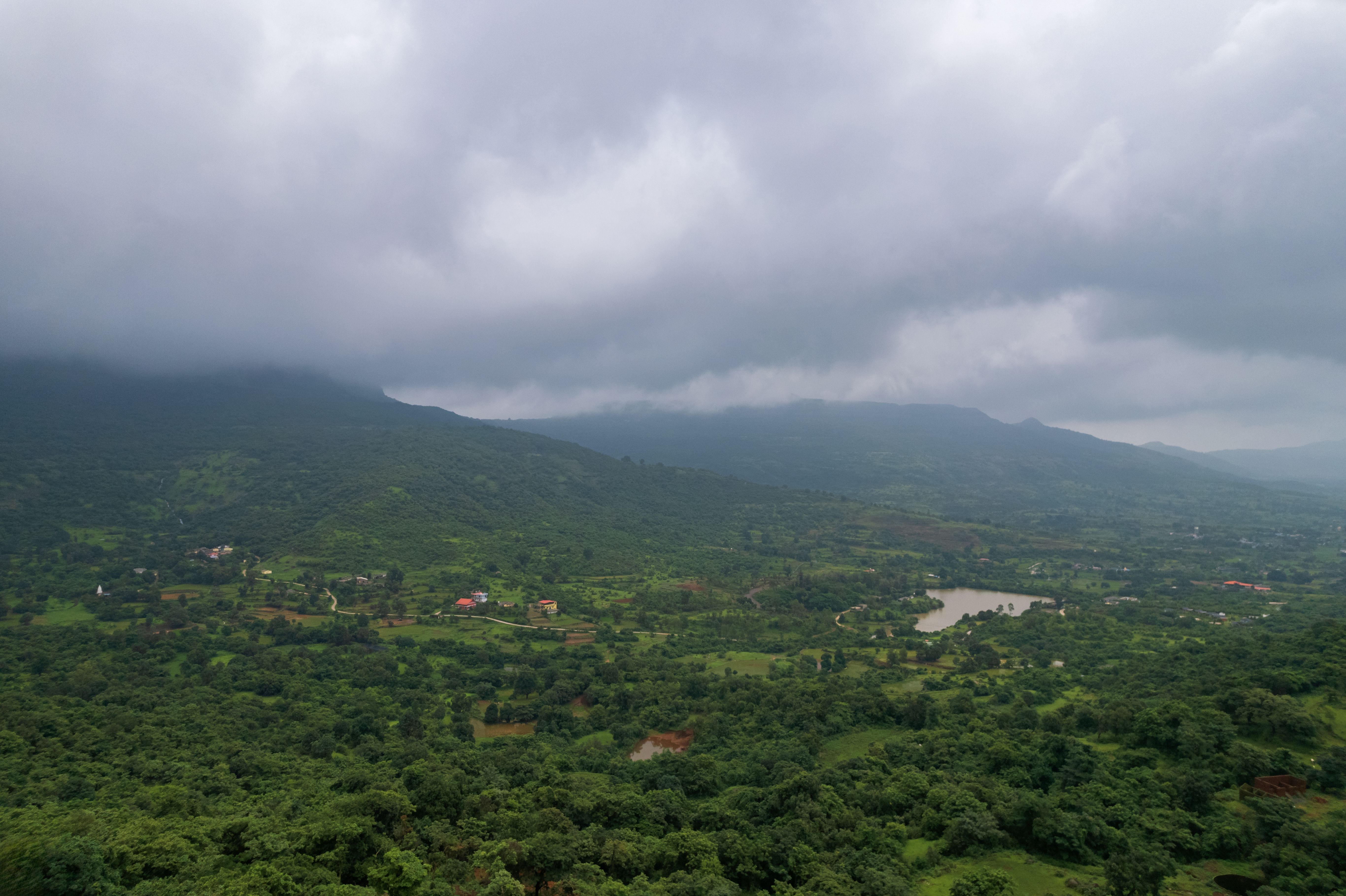 An aerial view of a lush green landscape with hills and cloudy skies, perfect for nature enthusiasts.