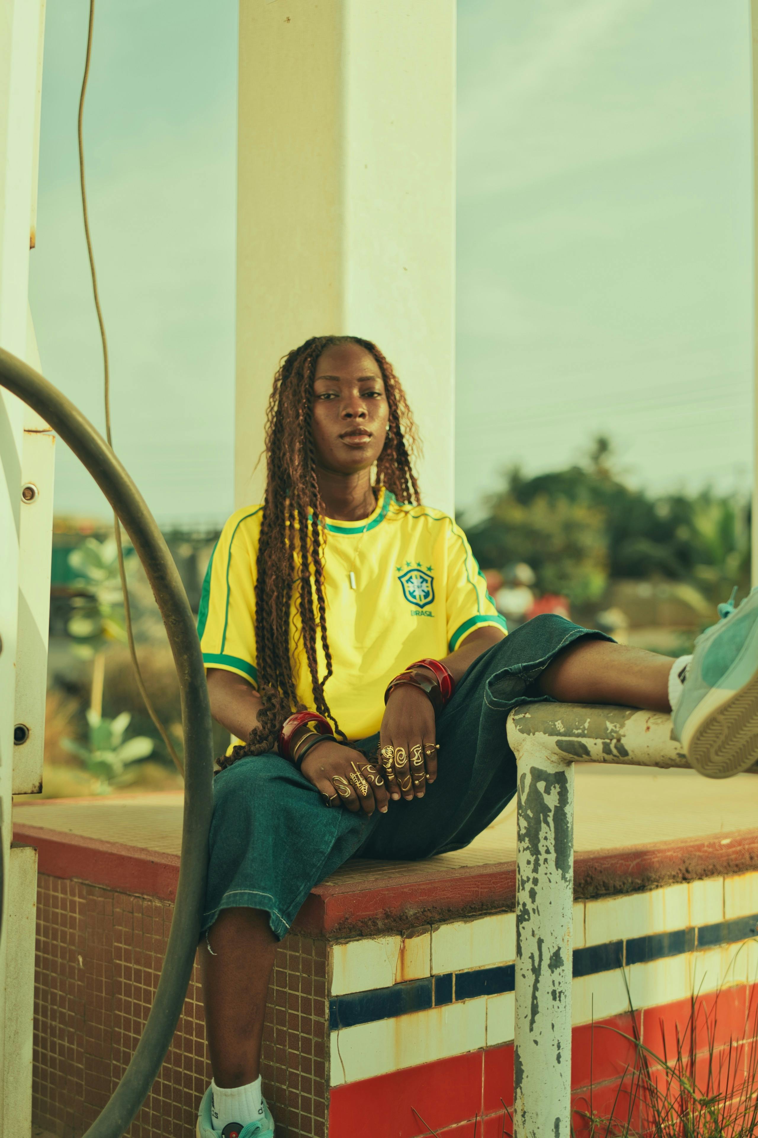 gratis Een stijlvolle jonge vrouw zit bij een verlaten, ouderwets benzinestation. Stockfoto