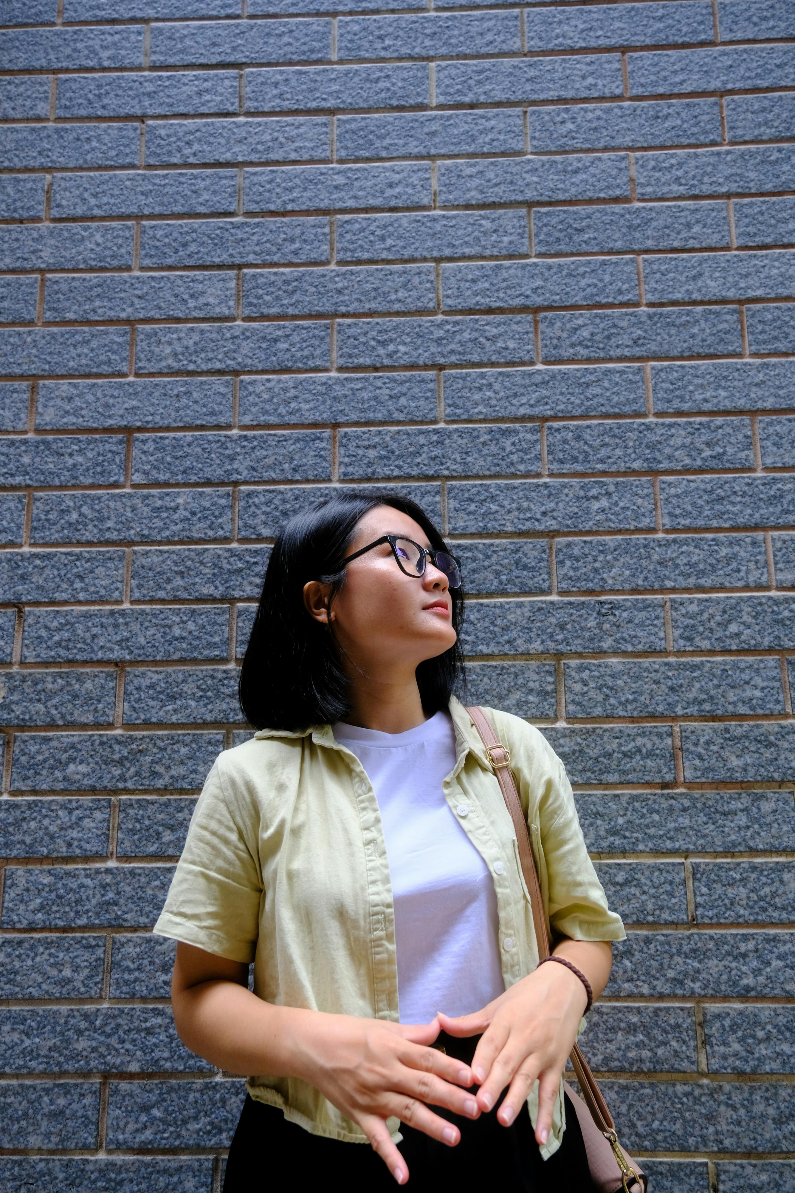 ฟรี ภาพถ่ายที่สื่อความหมายลึกซึ้งของหญิงสาวคนหนึ่งที่ยืนพิงกำแพงอิฐที่มีลวดลายในเมืองเว้ ประเทศเวียดนาม คลังภาพถ่าย