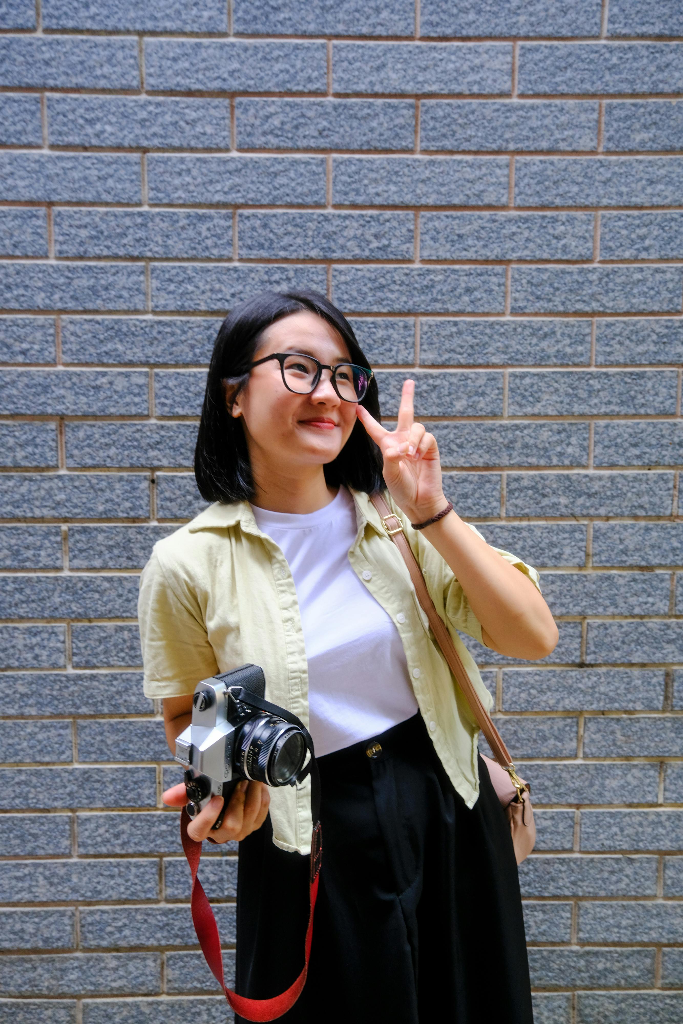 무료 베트남 후에에서 평화의 손짓을 하며 미소 짓는 여성 사진작가. 스톡 사진