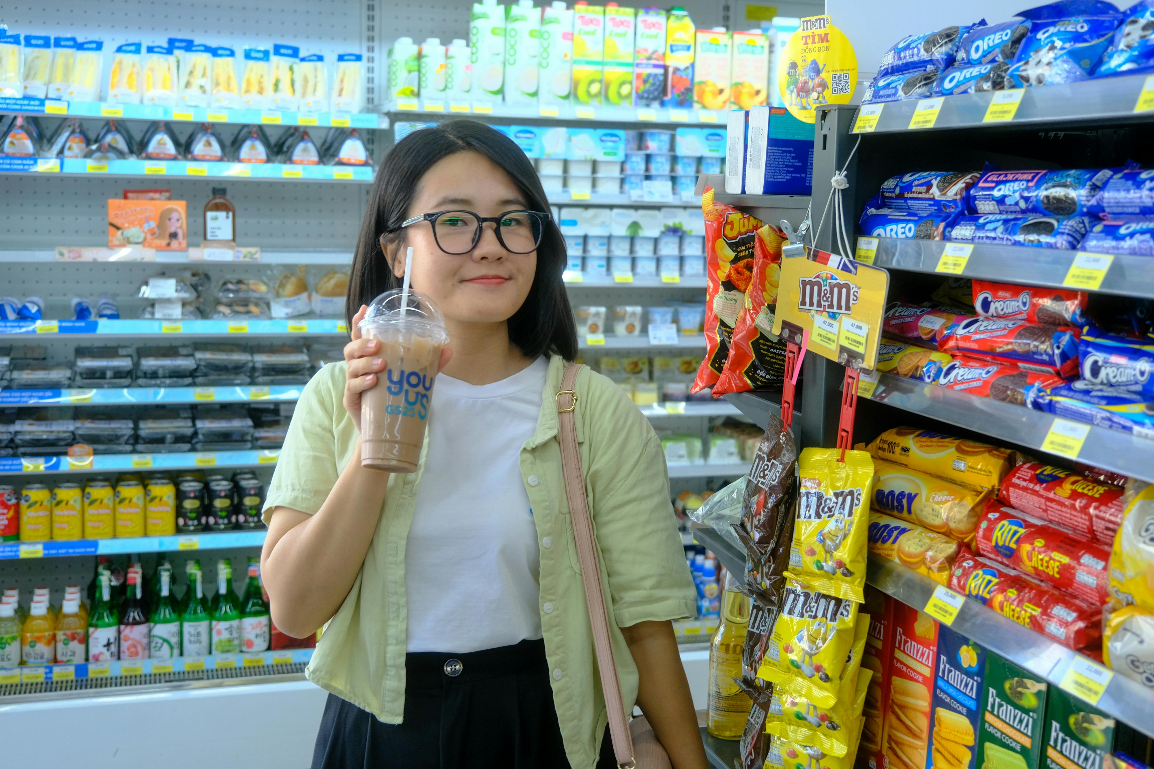 bezplatná Mladá žena si užívá drink při nakupování v obchodě s potravinami ve městě Hue ve Vietnamu. Základová fotografie