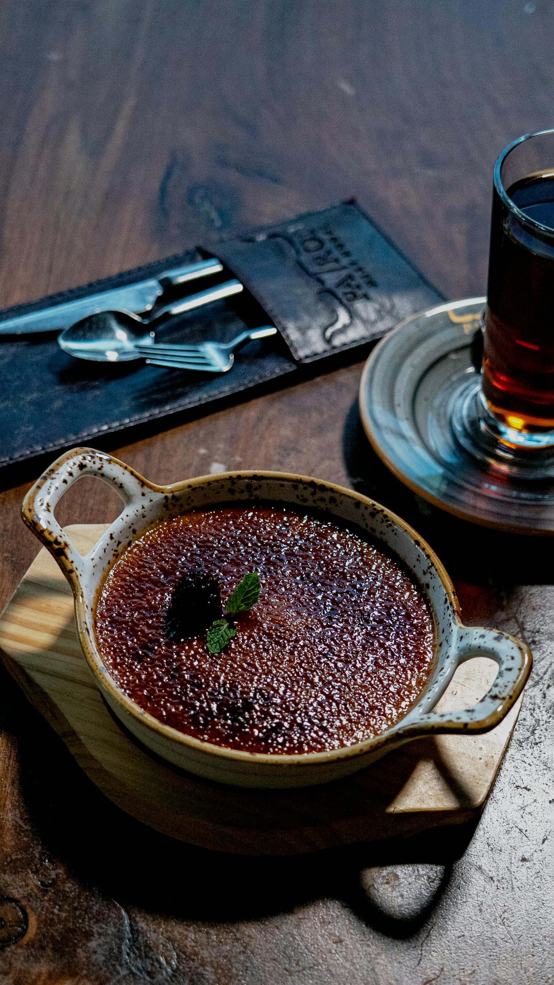 Gratis Rig crème brûlée-dessert med myntebladepynt serveret sammen med en varm drik. Lagerfoto