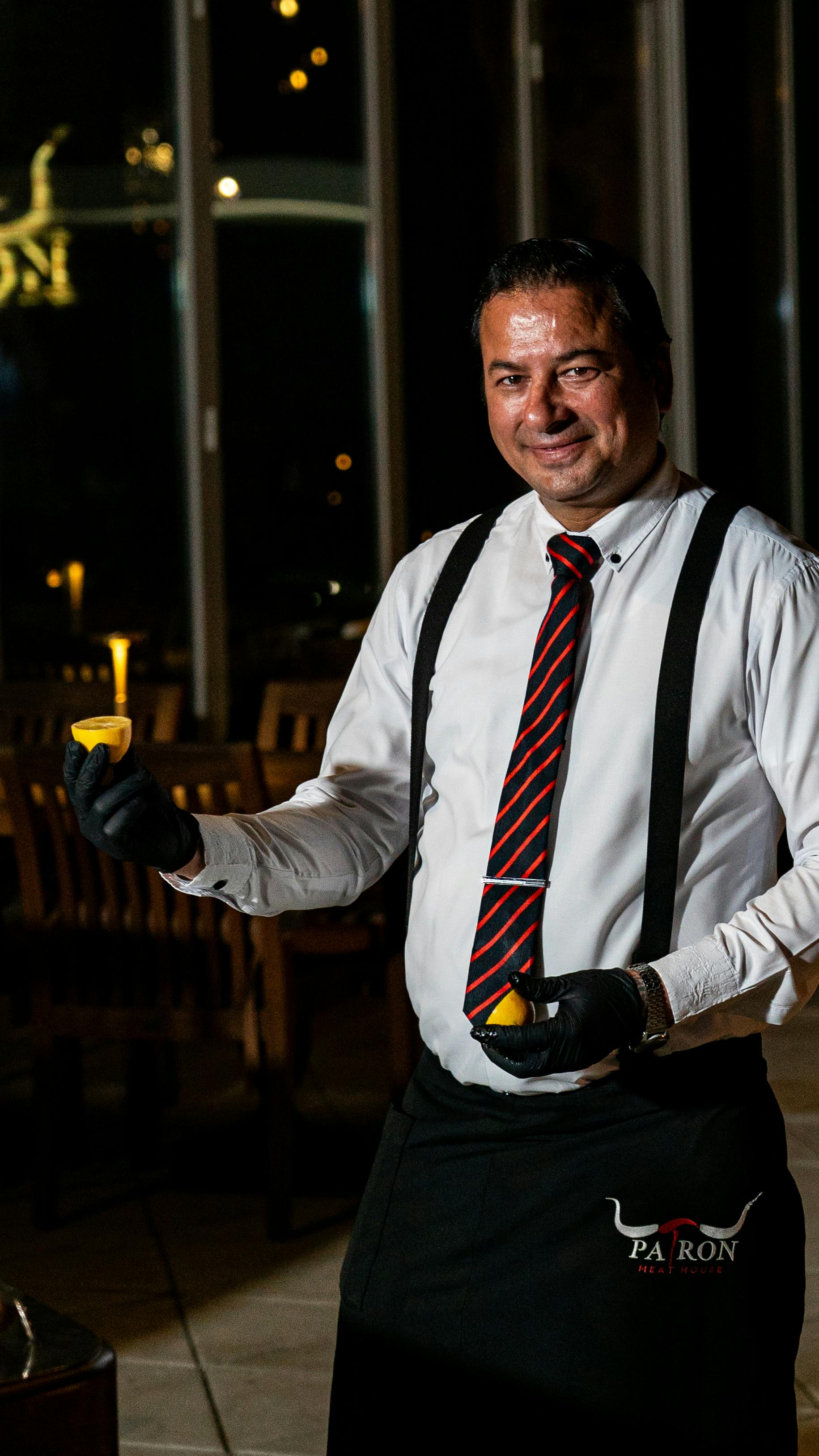 gratis Een lachende ober met citroenschijfjes in een restaurantomgeving, die een vleugje frisheid aan de ervaring toevoegt. Stockfoto