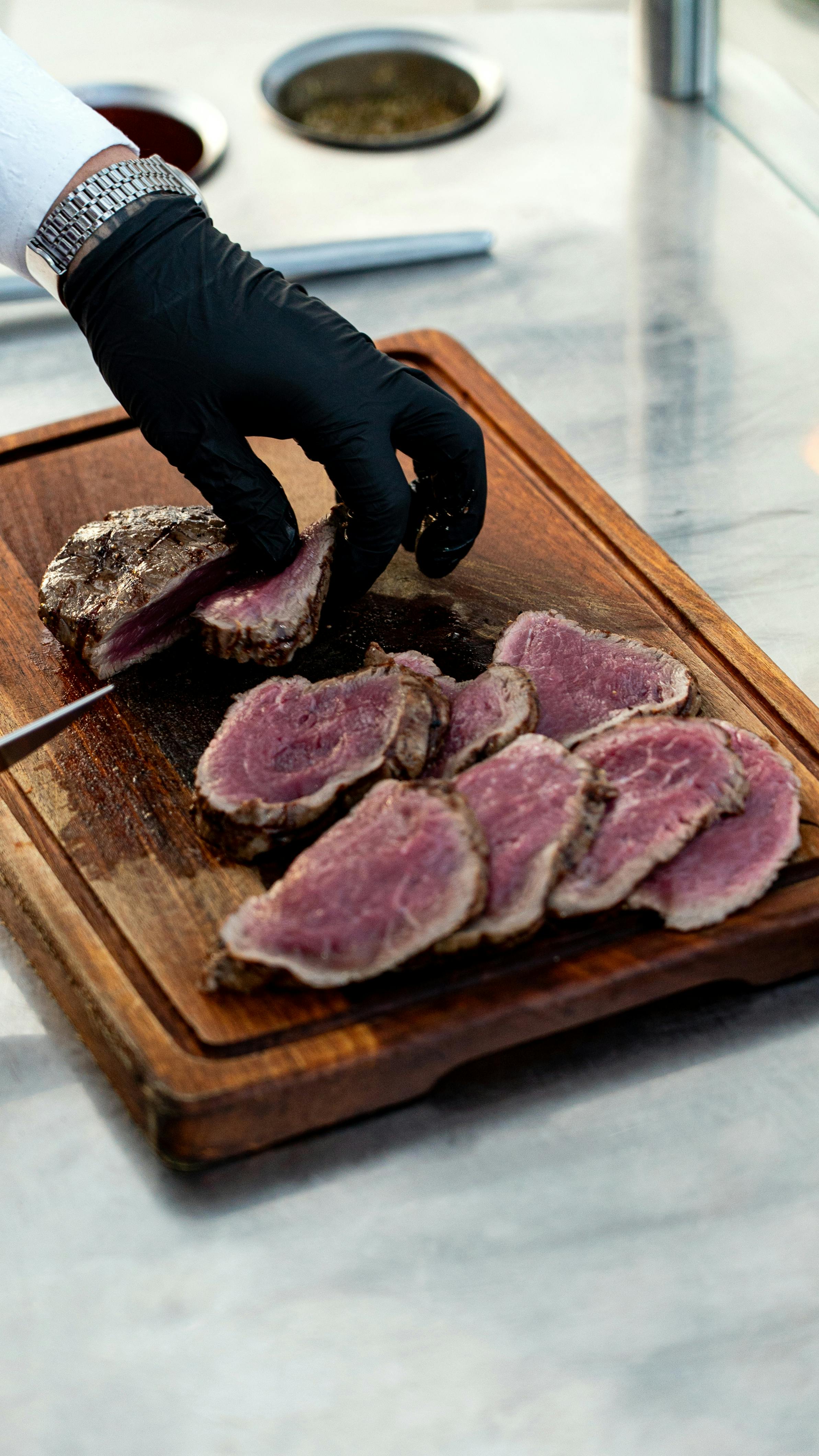 Gratis En kokk skjærer et medium-rare oksekjøttstykke på et trebrett, og viser frem ekspertkulinariske ferdigheter. Arkivbilde