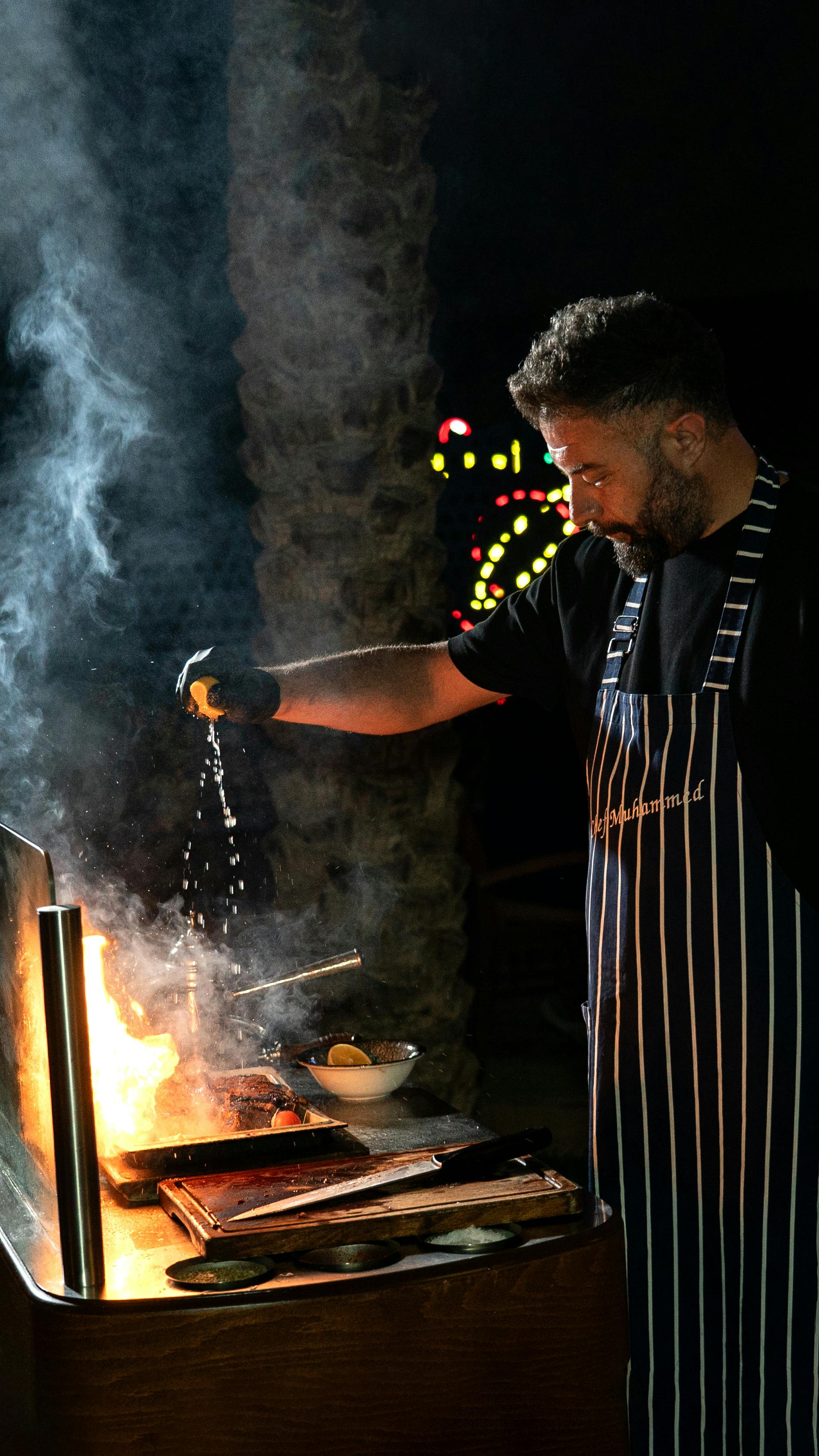 Gratis Kokken griller ekspertisemæssigt med flammer og røg og tilsætter krydderier for bedre smag om aftenen. Lagerfoto