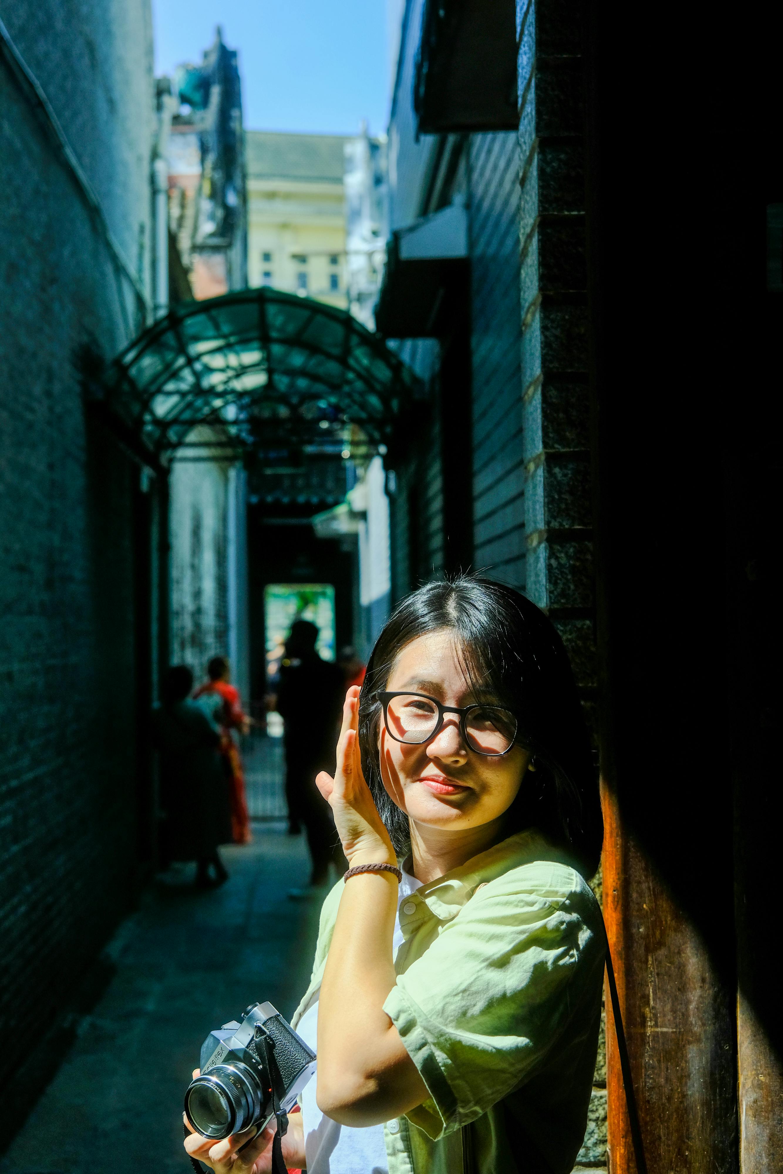 ฟรี ภาพถ่ายหญิงสาวคนหนึ่งกำลังถ่ายรูปในตรอกที่มีแสงแดดส่องถึงในเมืองเว้ ประเทศเวียดนาม คลังภาพถ่าย