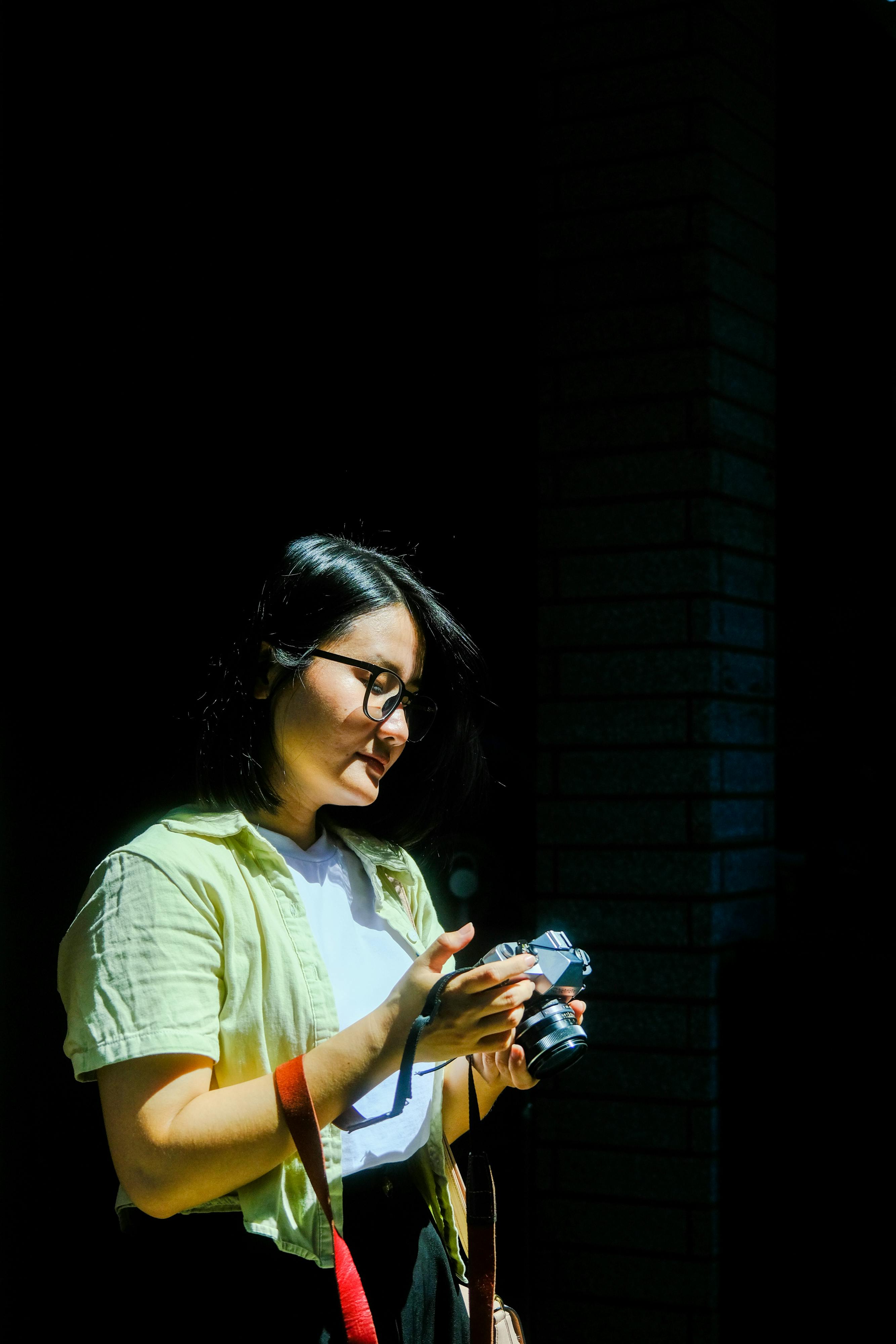 Gratis En ung kvinne undersøker et vintagekamera i skyggefullt sollys og fanger essensen av å reise i Hue i Vietnam. Arkivbilde