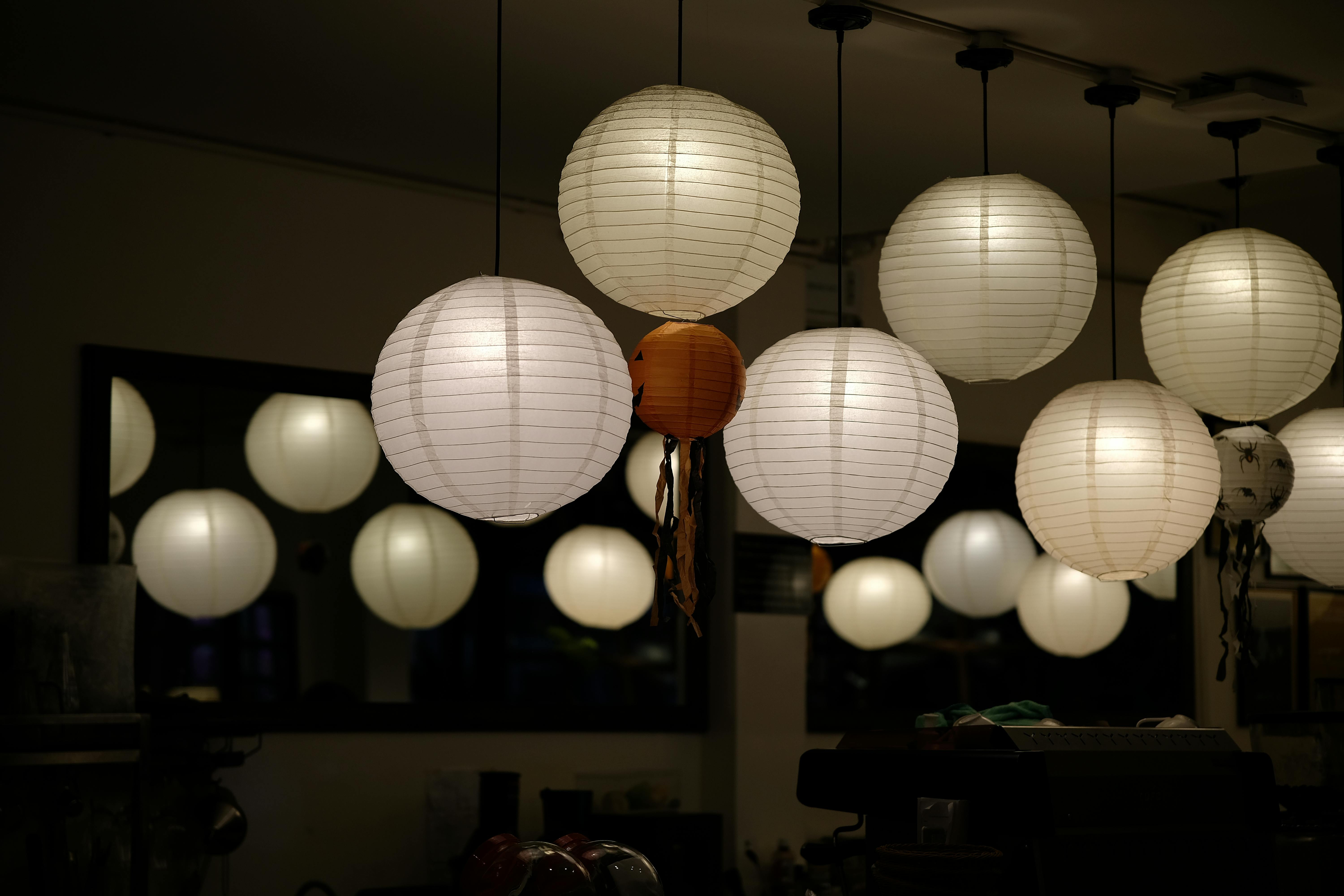 Gratis Un ambiente interno accogliente, illuminato da lanterne di carta rotonde e luminose che creano un'atmosfera calda e suggestiva. Foto a disposizione