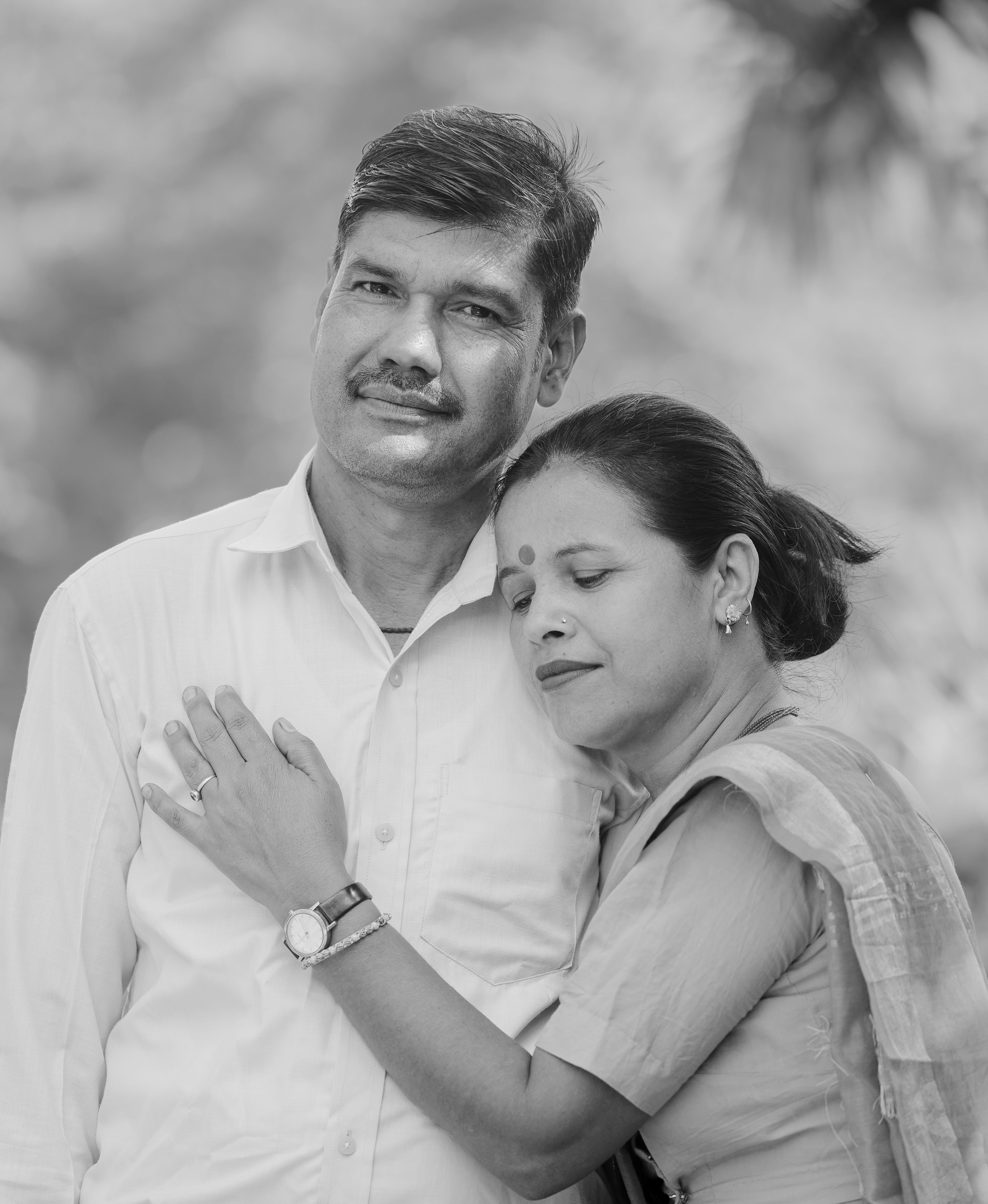 A serene black and white portrait of an affectionate couple embracing outdoors.