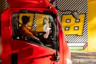 Man Driving Red Vehicle Past Vibrant Wall Mural