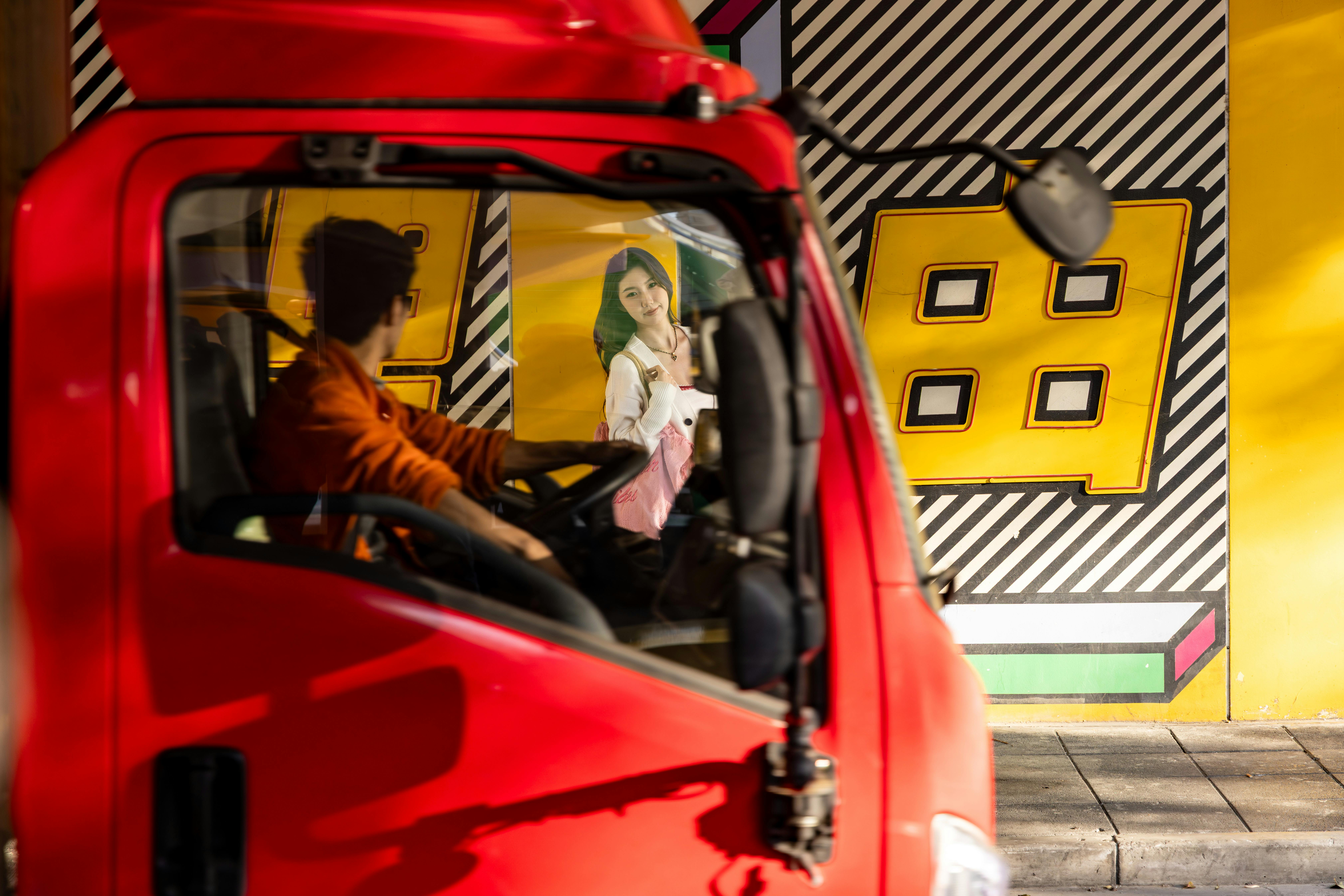 gratis Een man in een rode auto bekijkt op een zonnige dag een kleurrijke muurschildering. Stockfoto