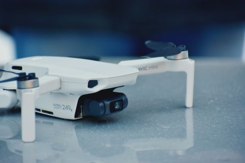 Free Close-up of a white drone on a reflective surface, showcasing its camera and sleek design. Stock Photo