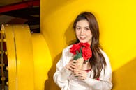Smiling Woman Holding Flowers in Yellow Background