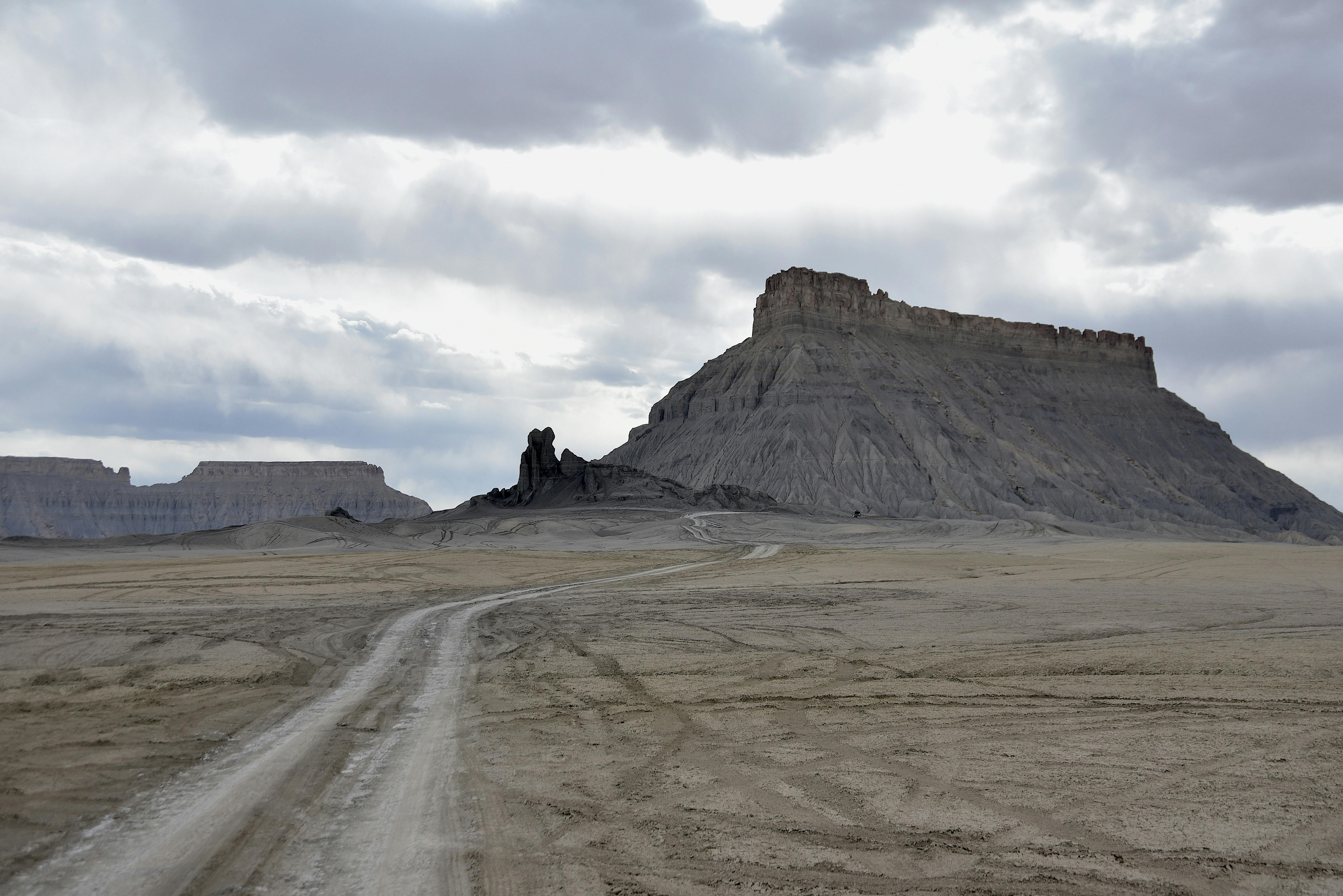 Bezpłatne Urzekający widok pustynnego krajobrazu z dzikim wzgórzem pod zachmurzonym niebem, idealny do tematyki podróżniczej. Zdjęcie z galerii