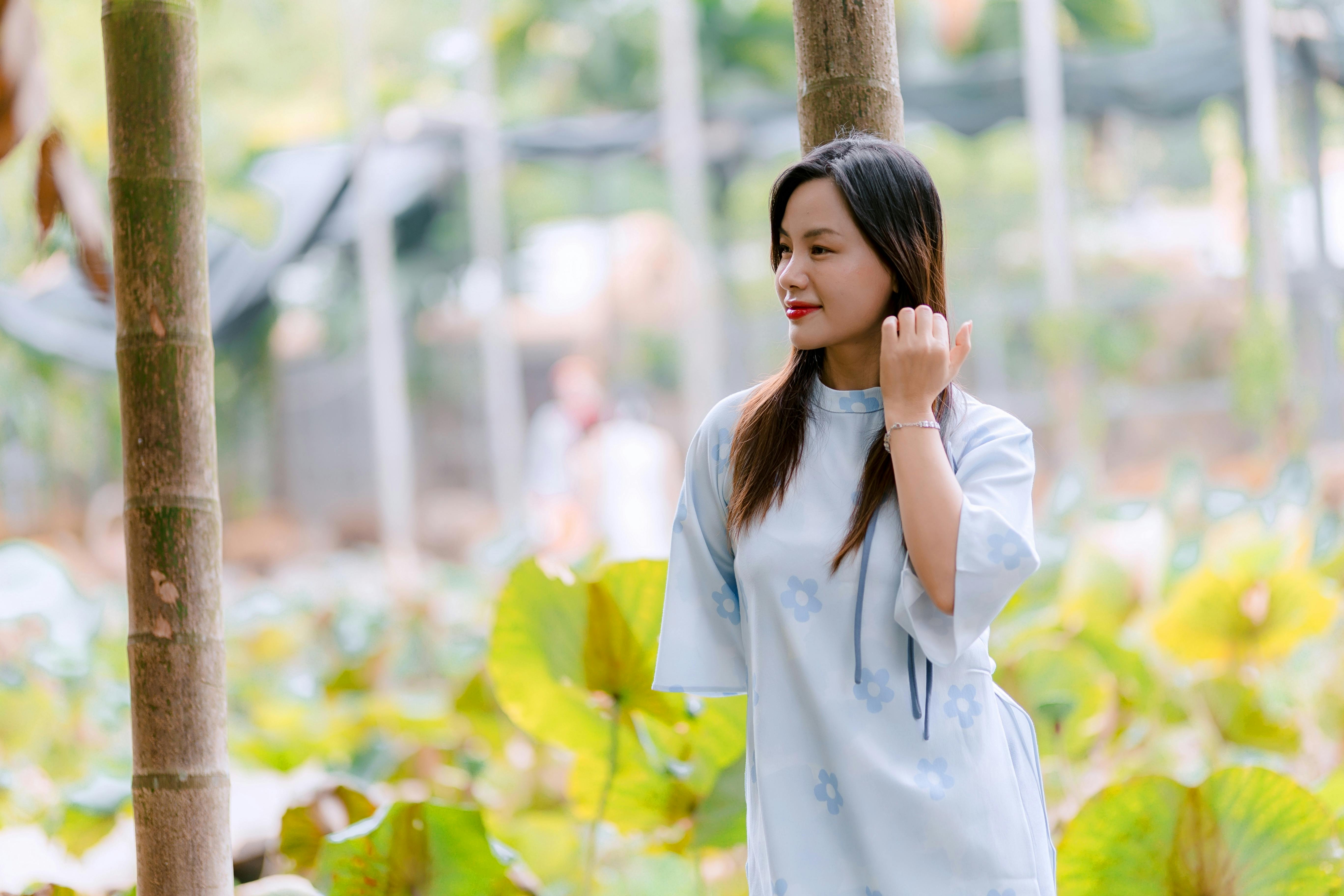 Gratuit O tânără femeie într-o rochie albastru deschis se bucură de un cadru senin în aer liber, cu verdeață. Fotografie de stoc