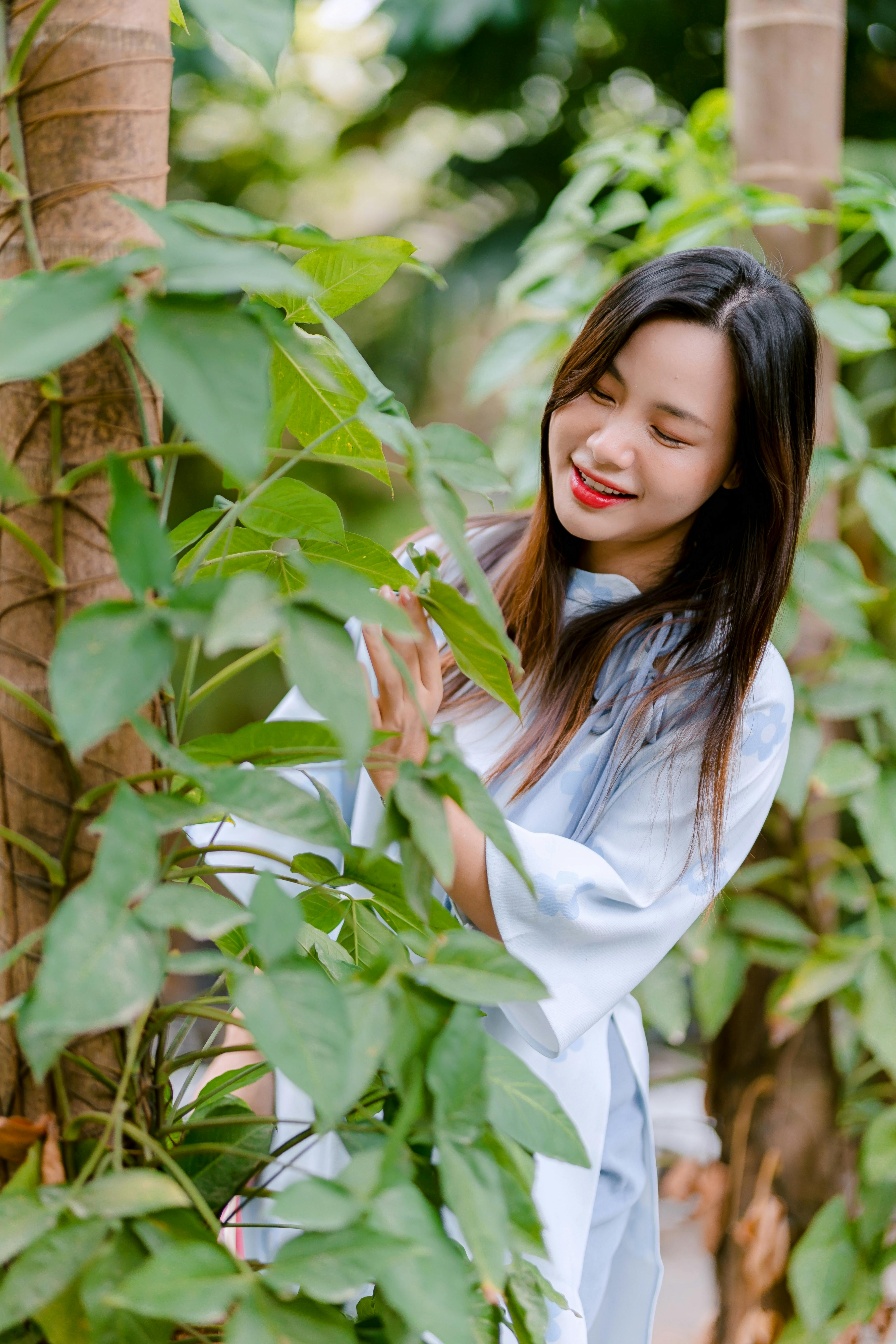 grátis Mulher sorridente aproveitando o tempo ao ar livre em um jardim verdejante. Foto profissional