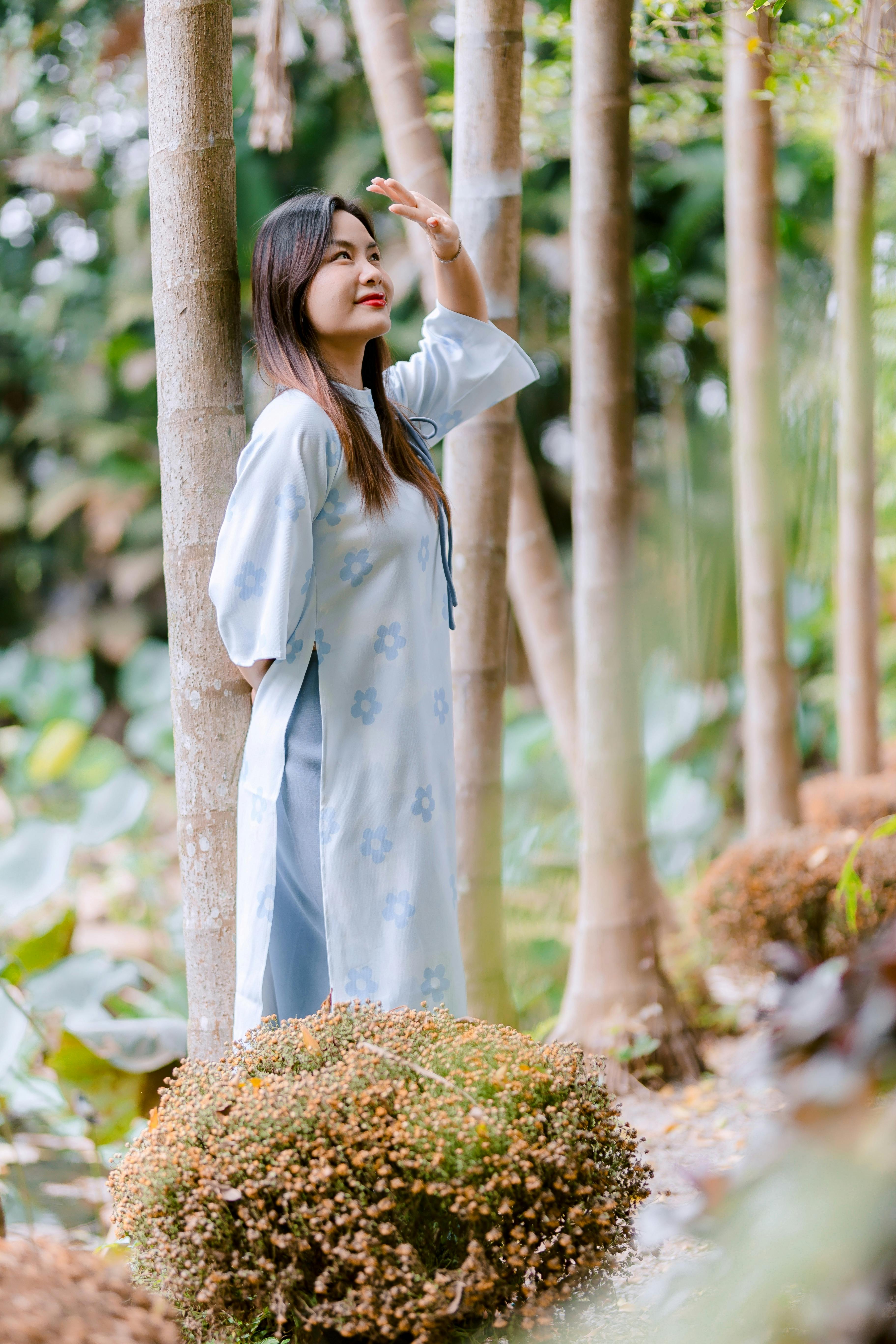 Gratis Kvinne i tradisjonell kjole nyter en fredelig skogomgivelse med sollys. Arkivbilde