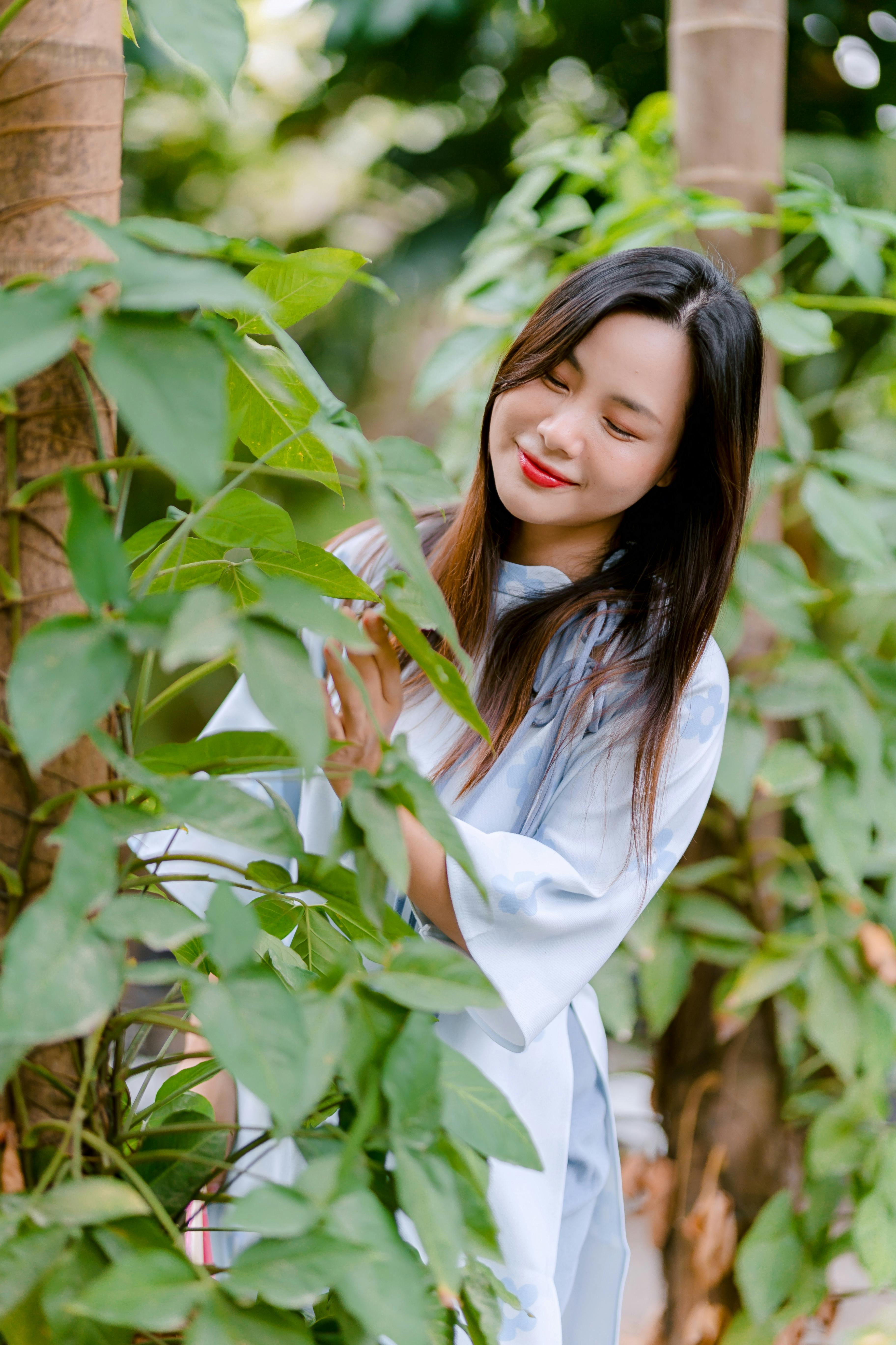gratis Jonge vrouw in een tuin, omgeven door weelderig groen, genietend van de natuur. Stockfoto