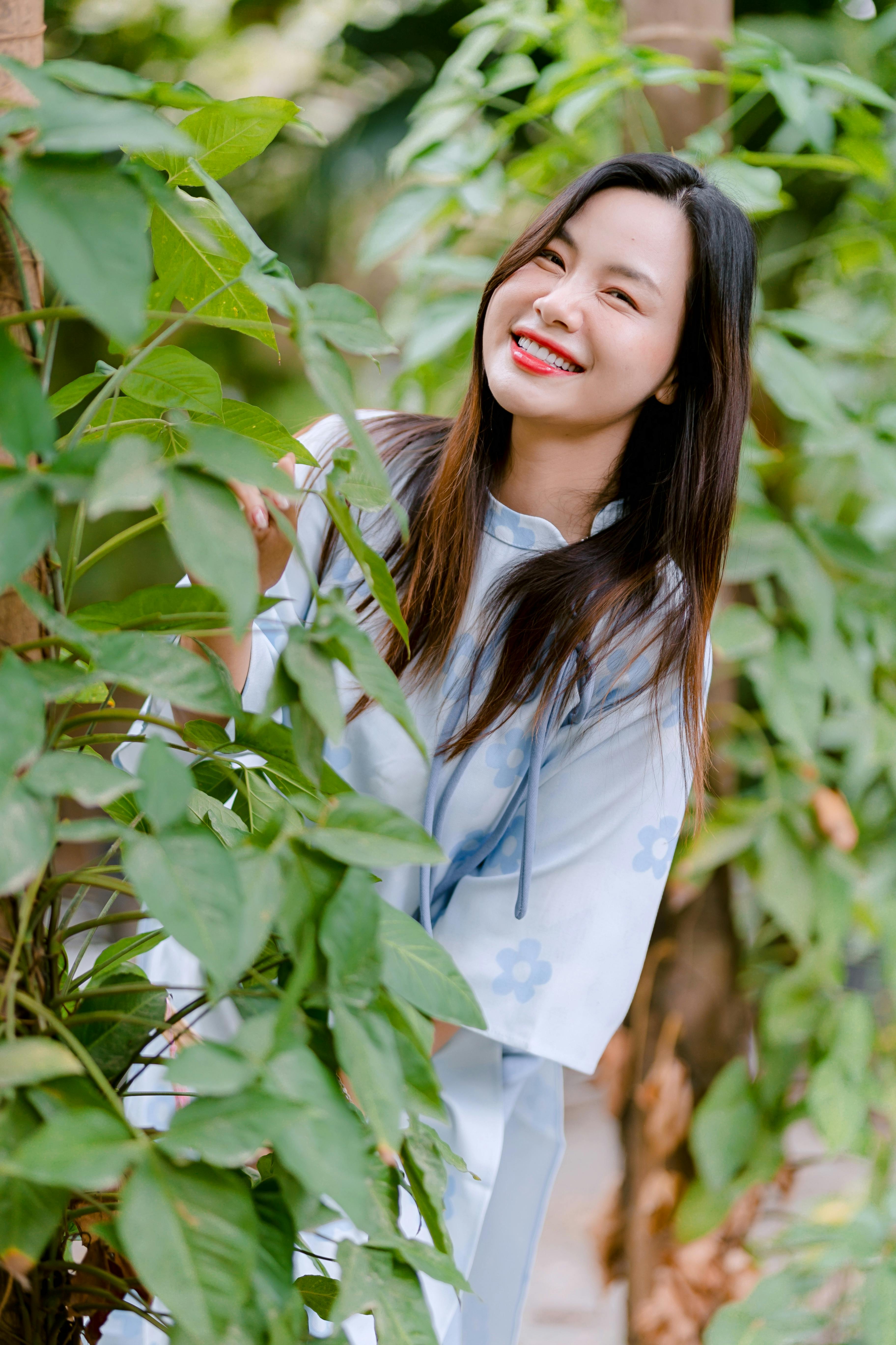 gratis Een vrolijke vrouw lacht te midden van groen gebladerte in de aangename zon. Stockfoto