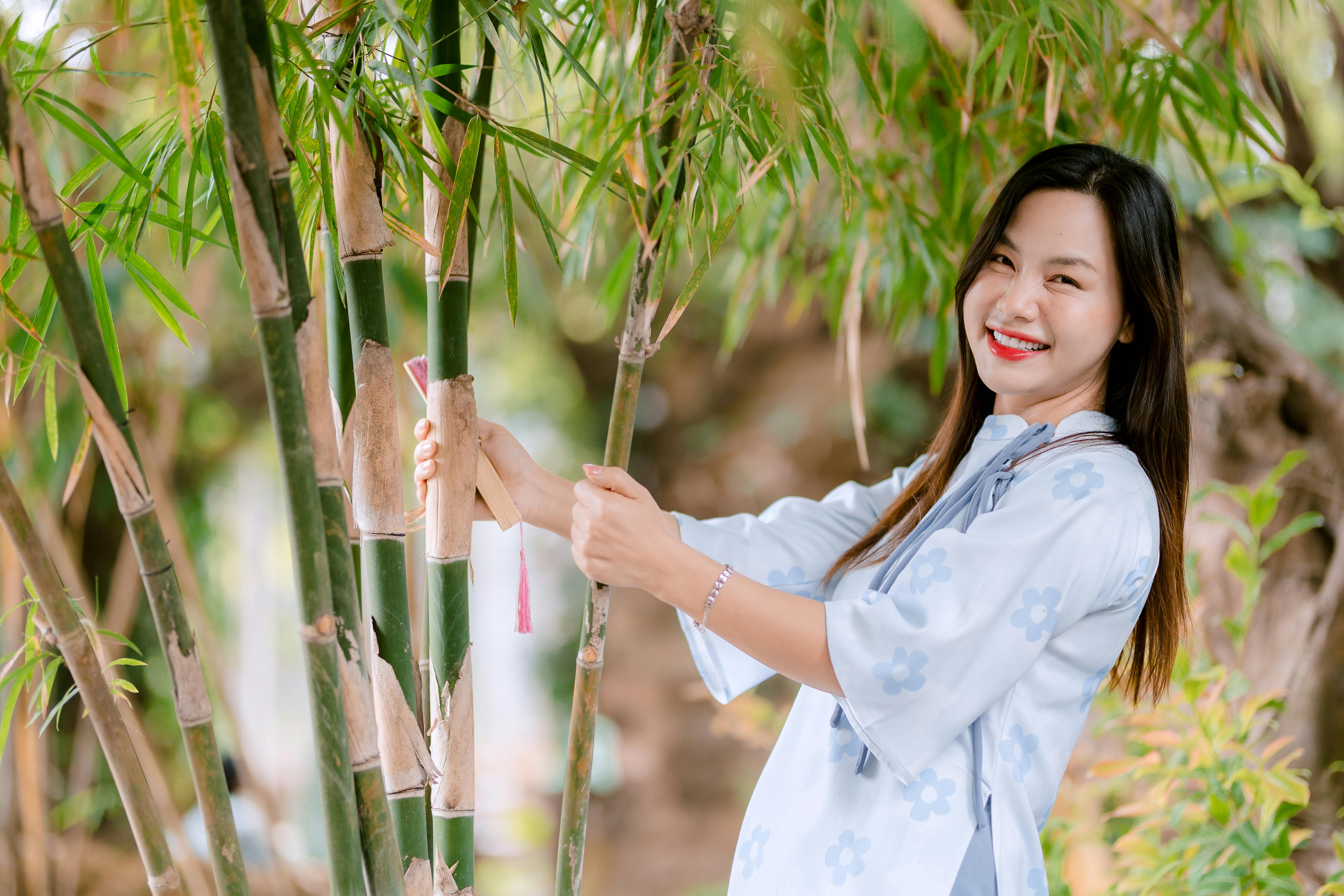 grátis Mulher feliz desfruta da natureza com bambu em ambiente externo. Foto profissional