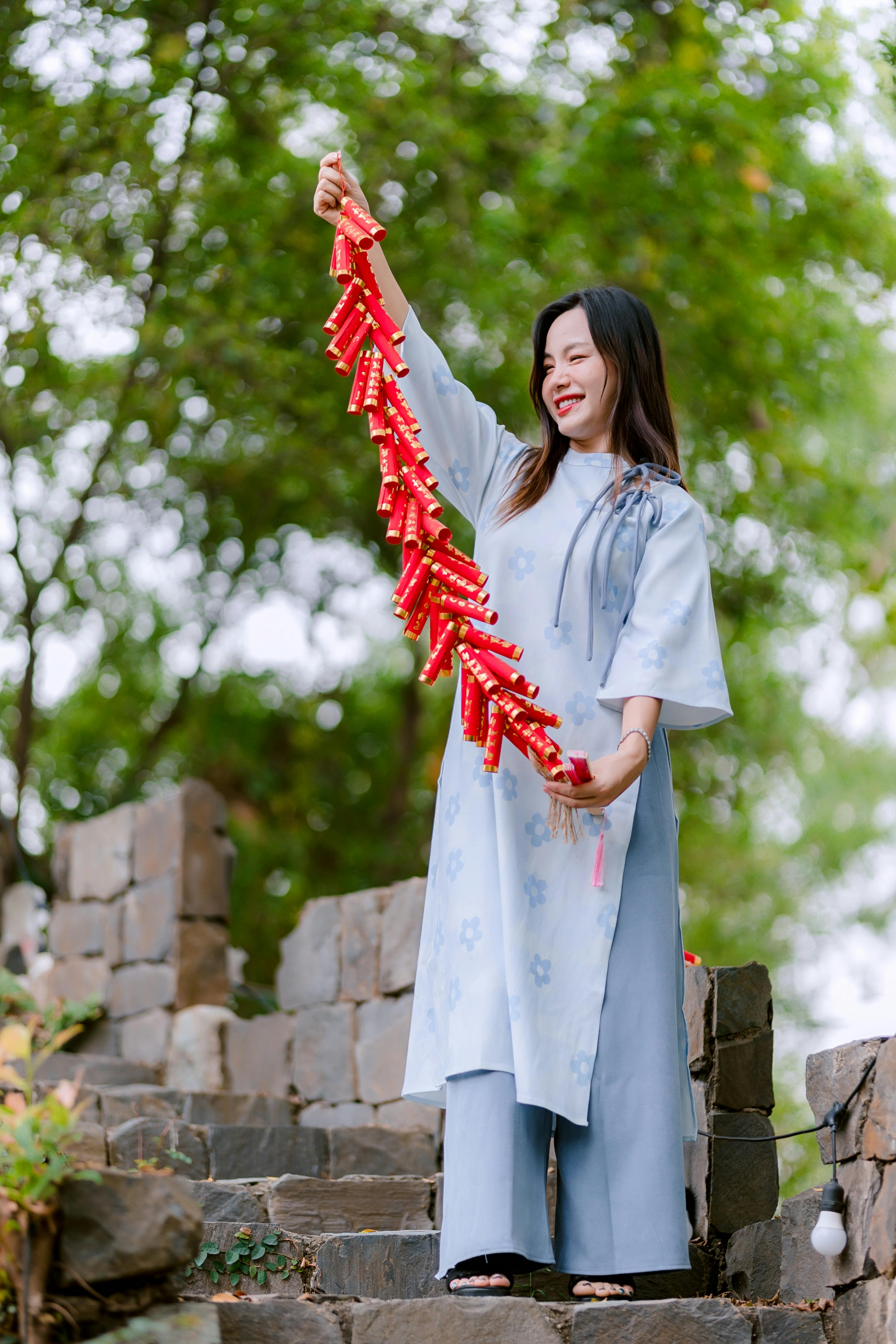 бесплатная Радостная женщина с красными фейерверками в руках празднует на открытом воздухе. Стоковое фото