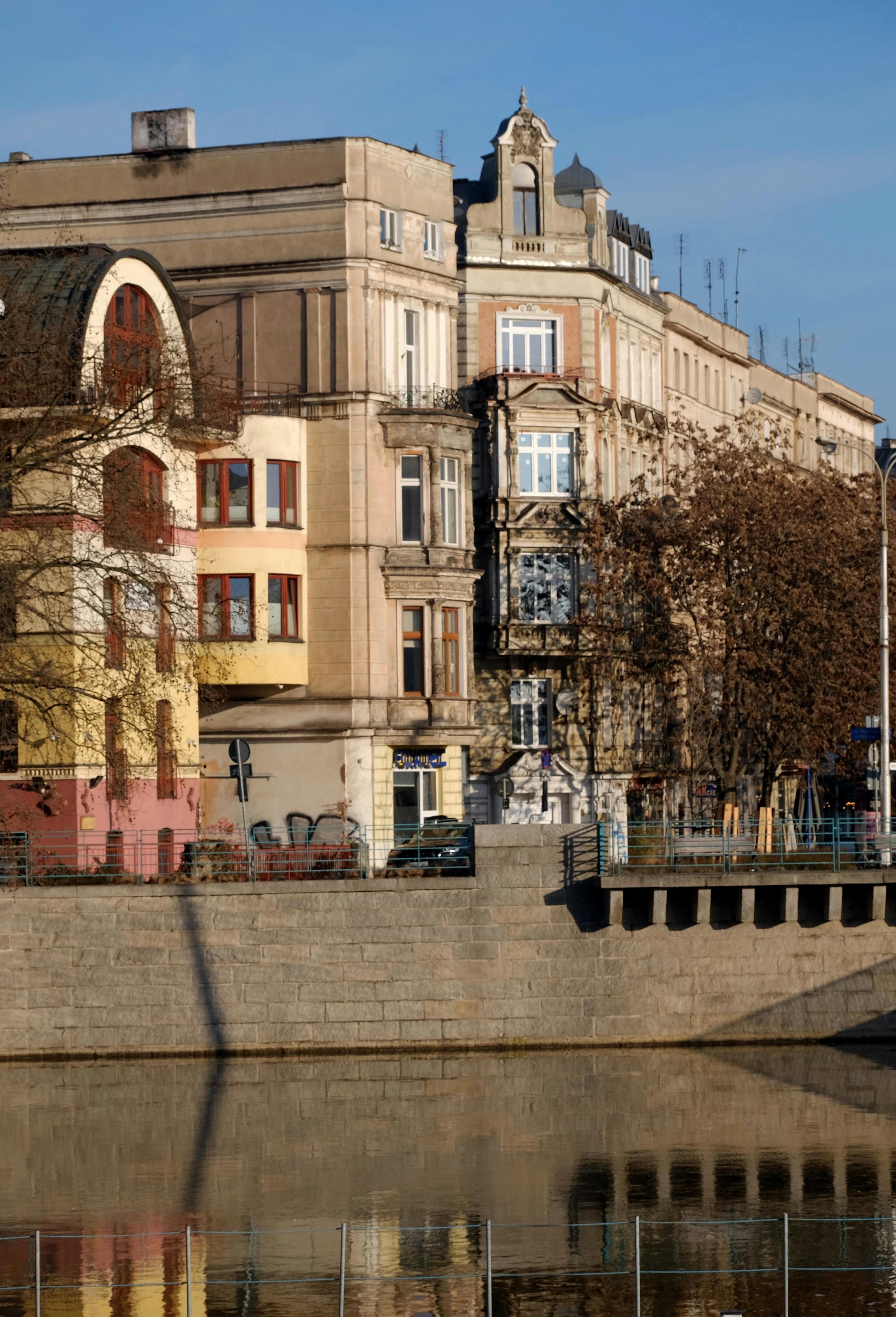 grátis Vista panorâmica de edifícios históricos europeus refletidos em um canal tranquilo, capturando o charme da arquitetura clássica. Foto profissional