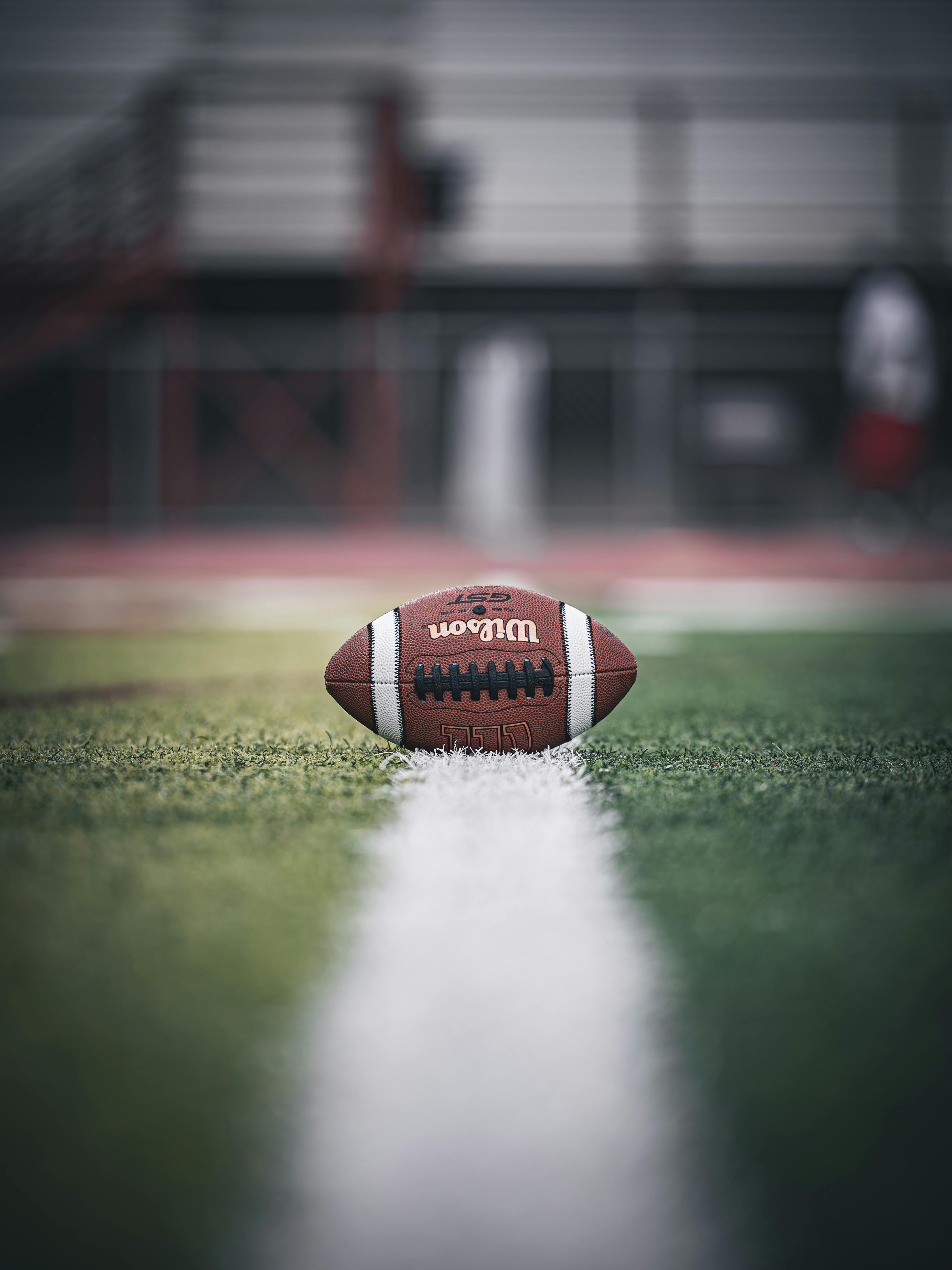 Gratuit Gros plan sur un ballon de football américain sur le terrain, soulignant l'ambiance du match. Photos