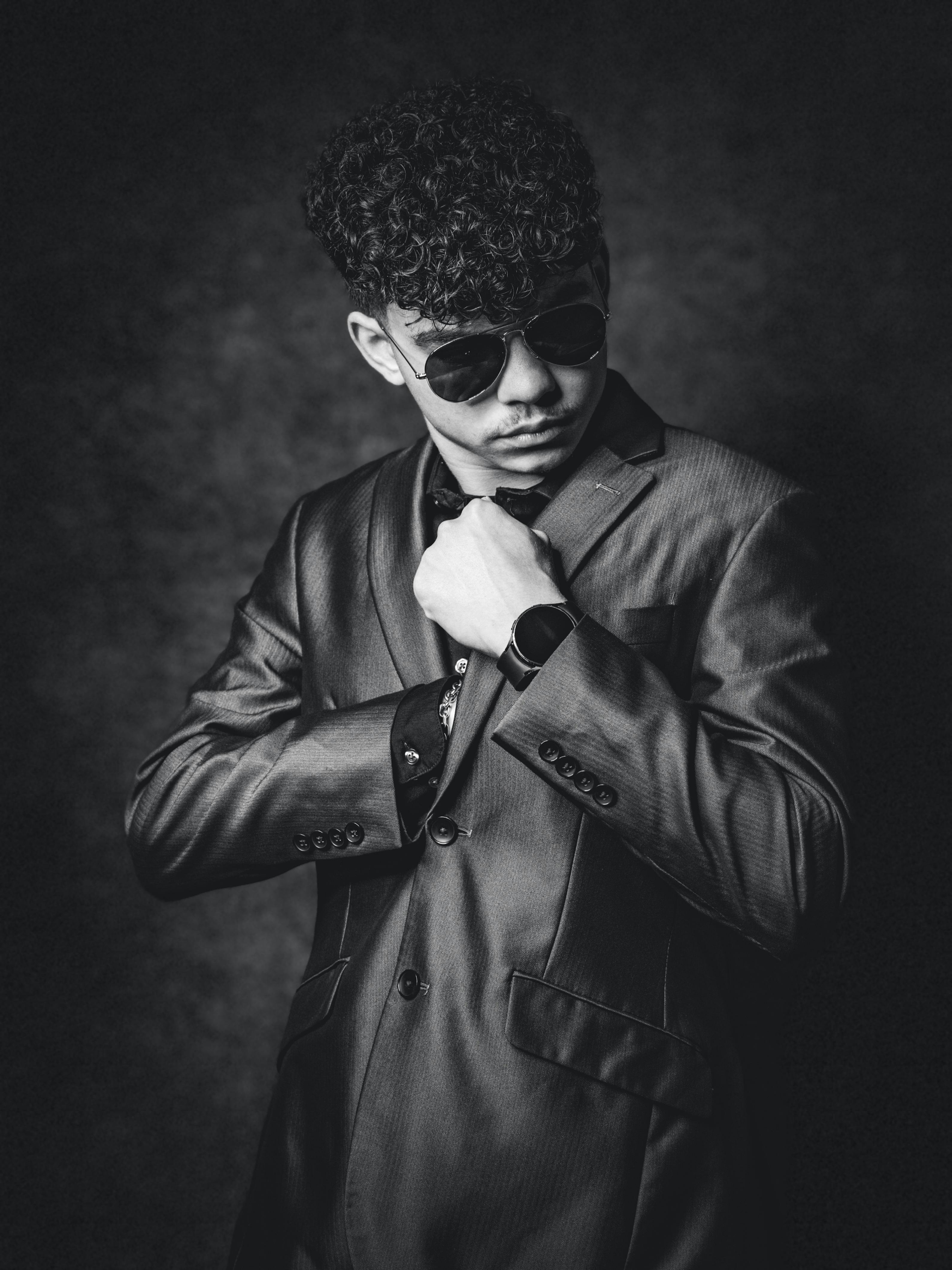 Gratis Elegante retrato de un hombre con traje ajustándose la corbata, con gafas de sol. Foto de stock