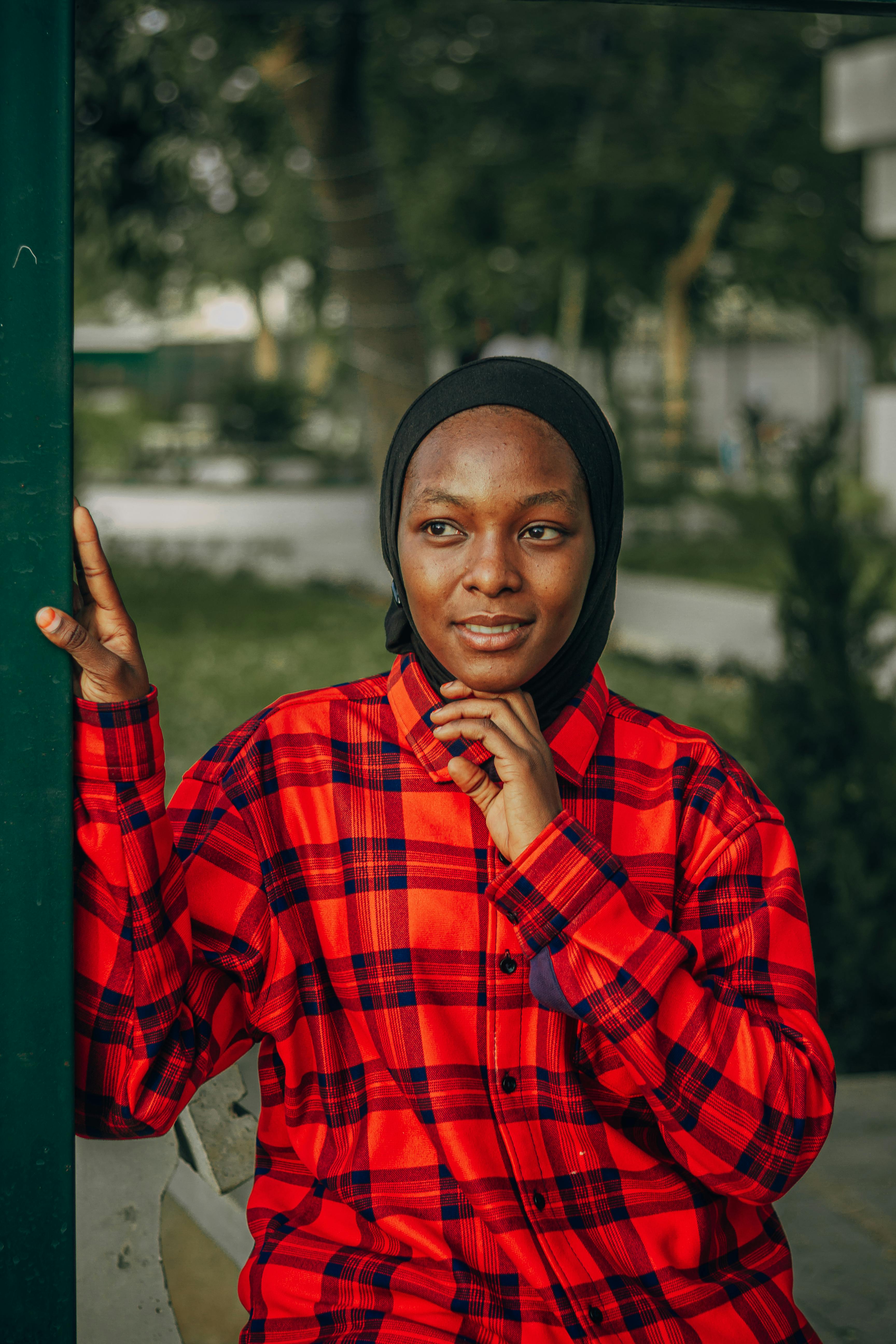 Ücretsiz Dış mekanda kırmızı ekose gömlek giyen genç bir kadının düşünceli bir ifadeyle çekilmiş portresi. Stok Fotoğraflar